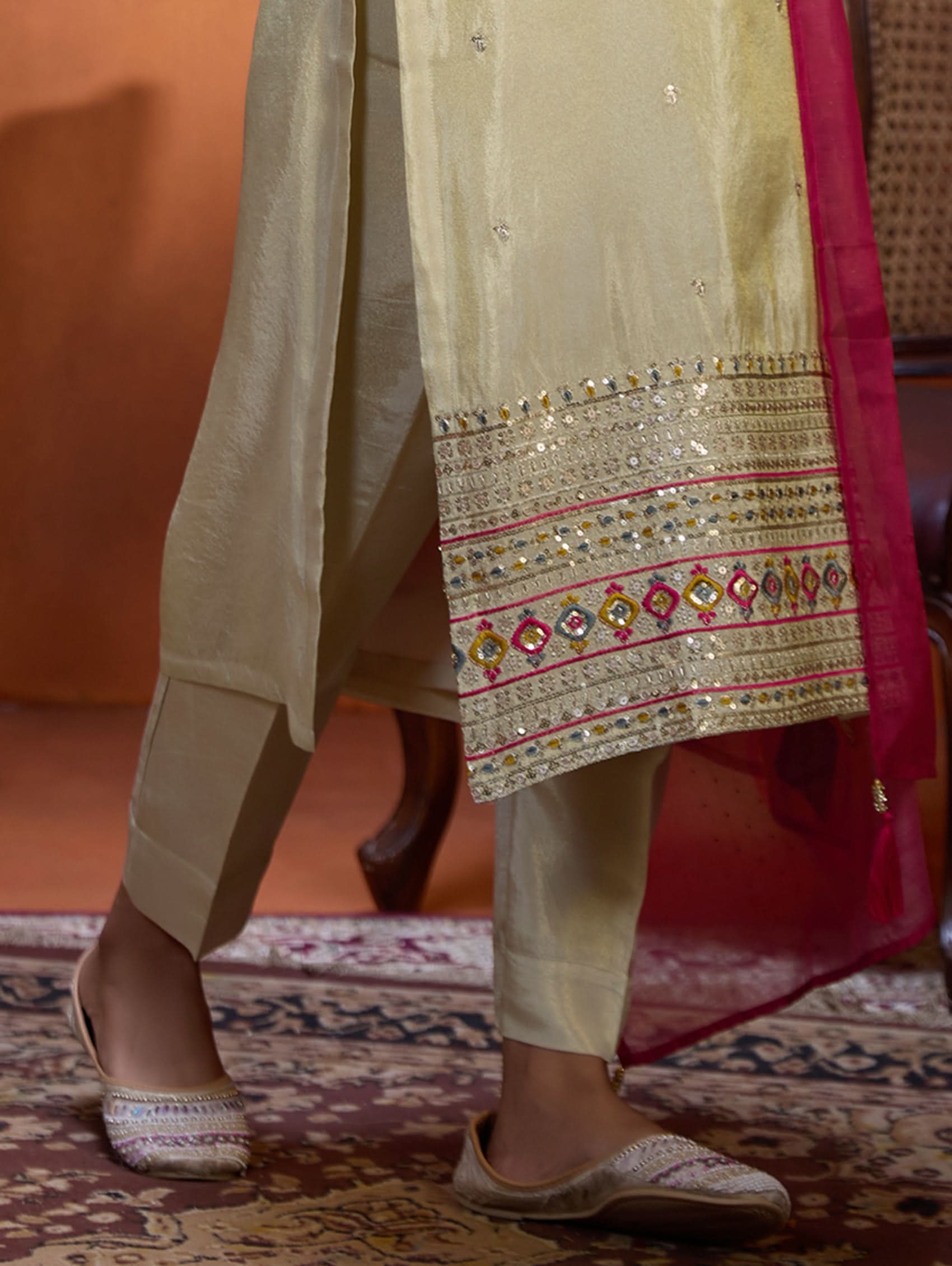 A woman wearing a traditional embroidered shimmer silk suit set with a round neckline, three-fourth sleeves, and a dupatta with digital printed chanderi silk.