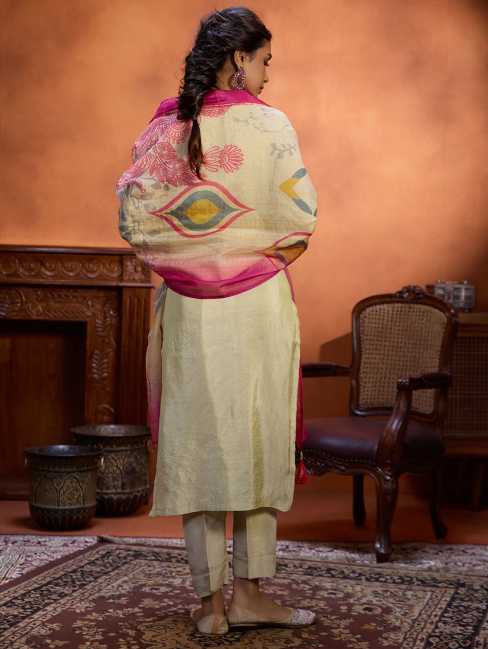 A woman wearing a traditional embroidered shimmer silk suit set with a round neckline, three-fourth sleeves, and a dupatta with digital printed chanderi silk.