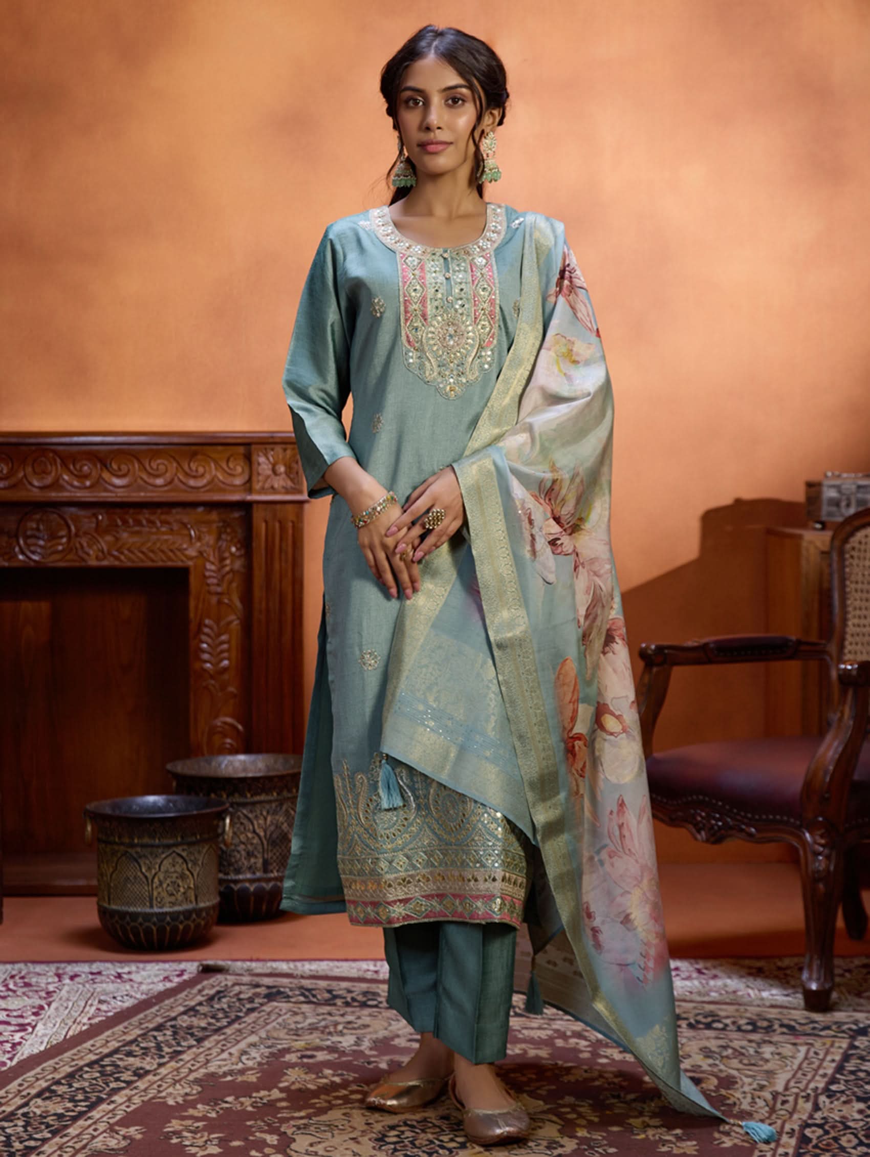 A woman wearing a blue suit set with embroidery, consisting of a kurta, pants, and a dupatta.