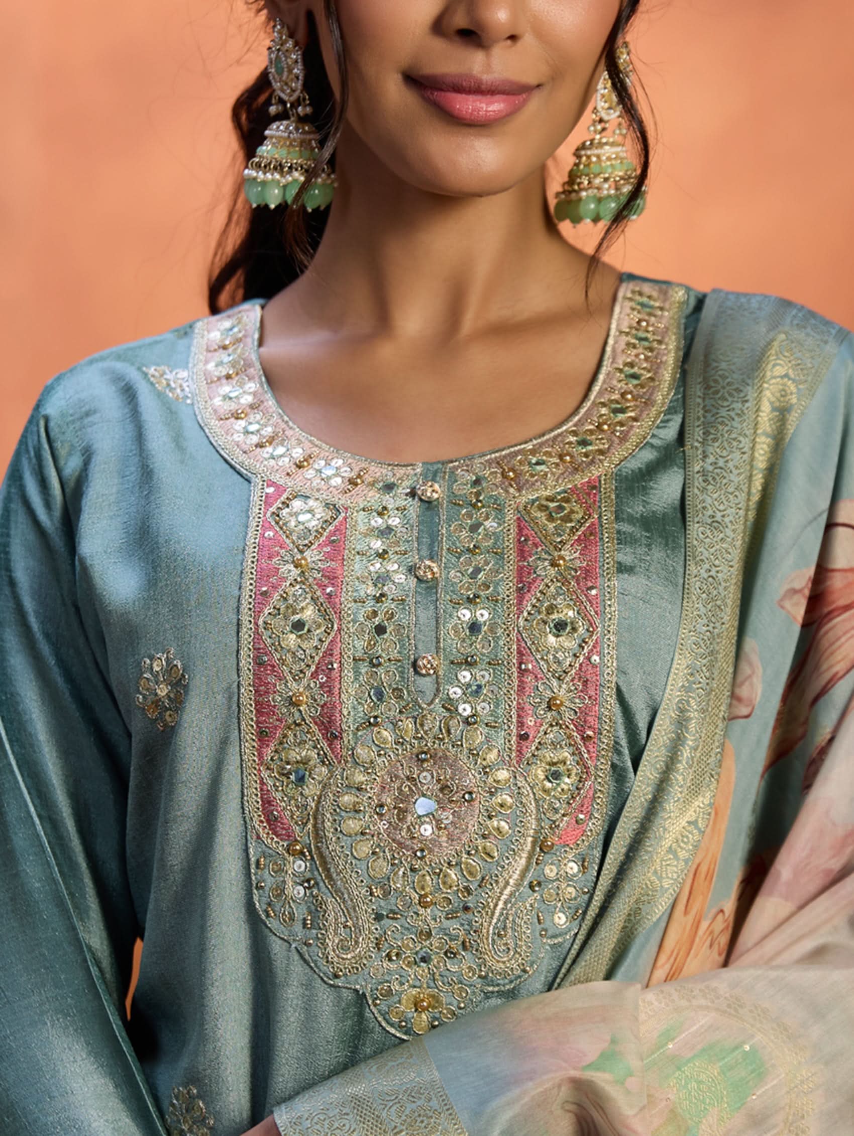 A woman wearing a blue suit set with embroidery, consisting of a kurta, pants, and a dupatta.