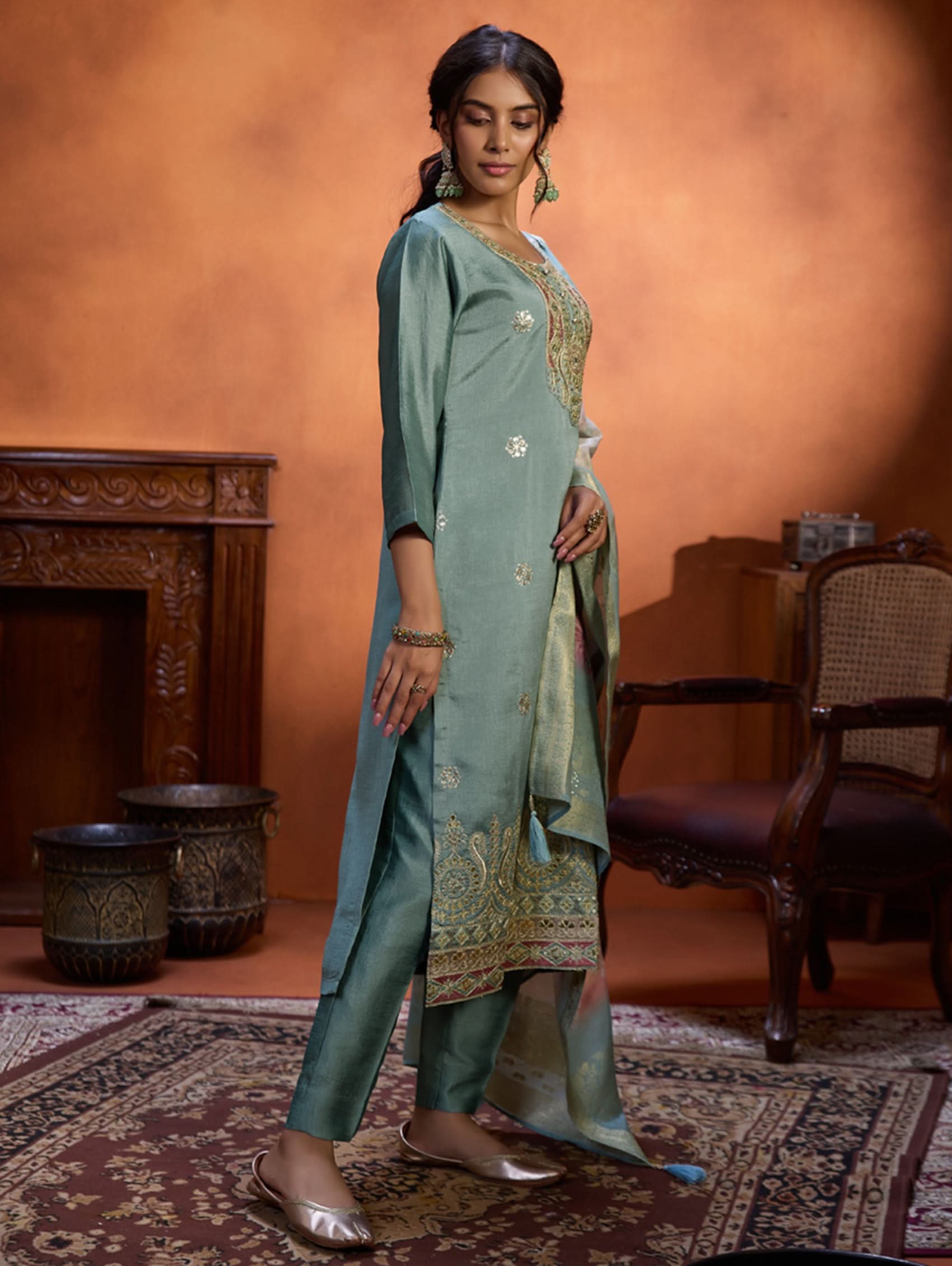 A woman wearing a blue suit set with embroidery, consisting of a kurta, pants, and a dupatta.