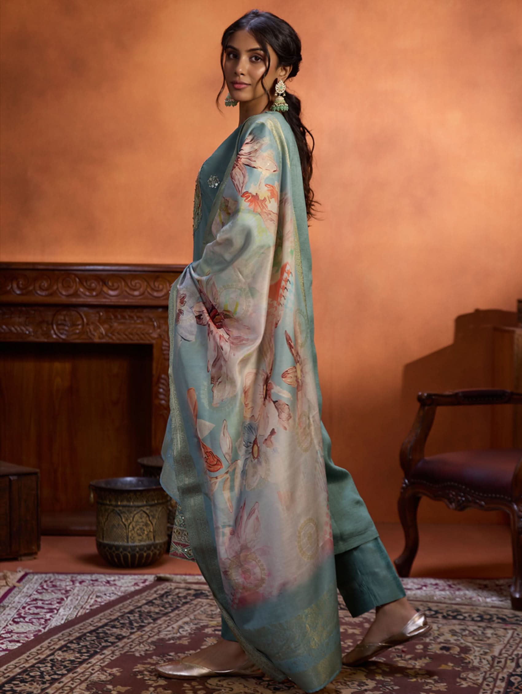 A woman wearing a blue suit set with embroidery, consisting of a kurta, pants, and a dupatta.
