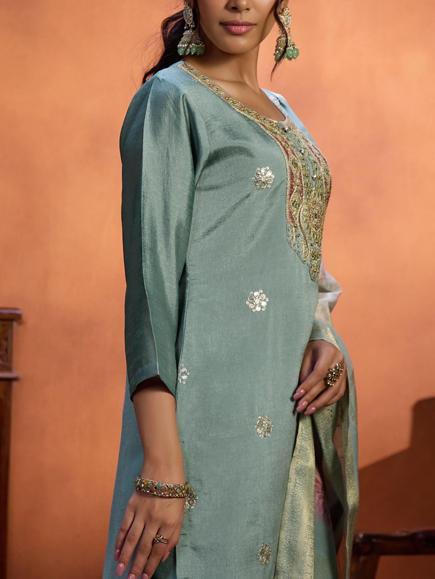 A woman wearing a blue suit set with embroidery, consisting of a kurta, pants, and a dupatta.