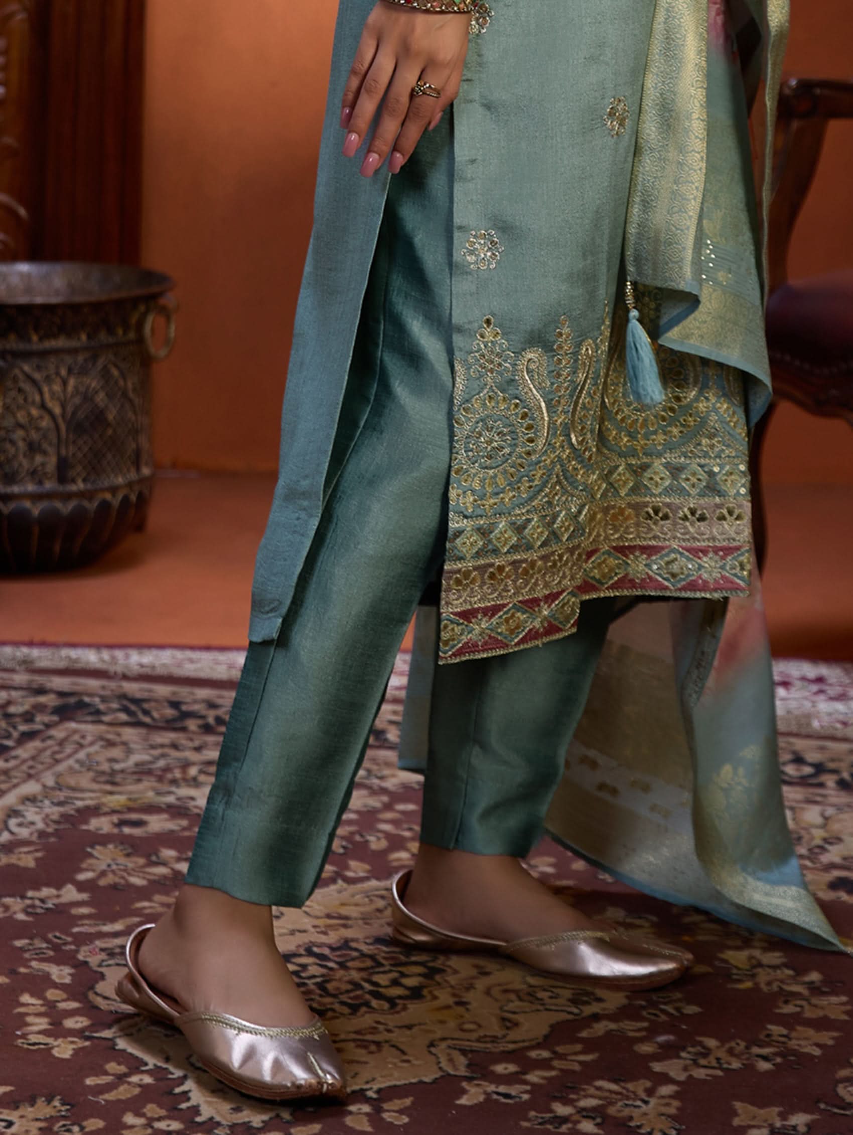 A woman wearing a blue suit set with embroidery, consisting of a kurta, pants, and a dupatta.
