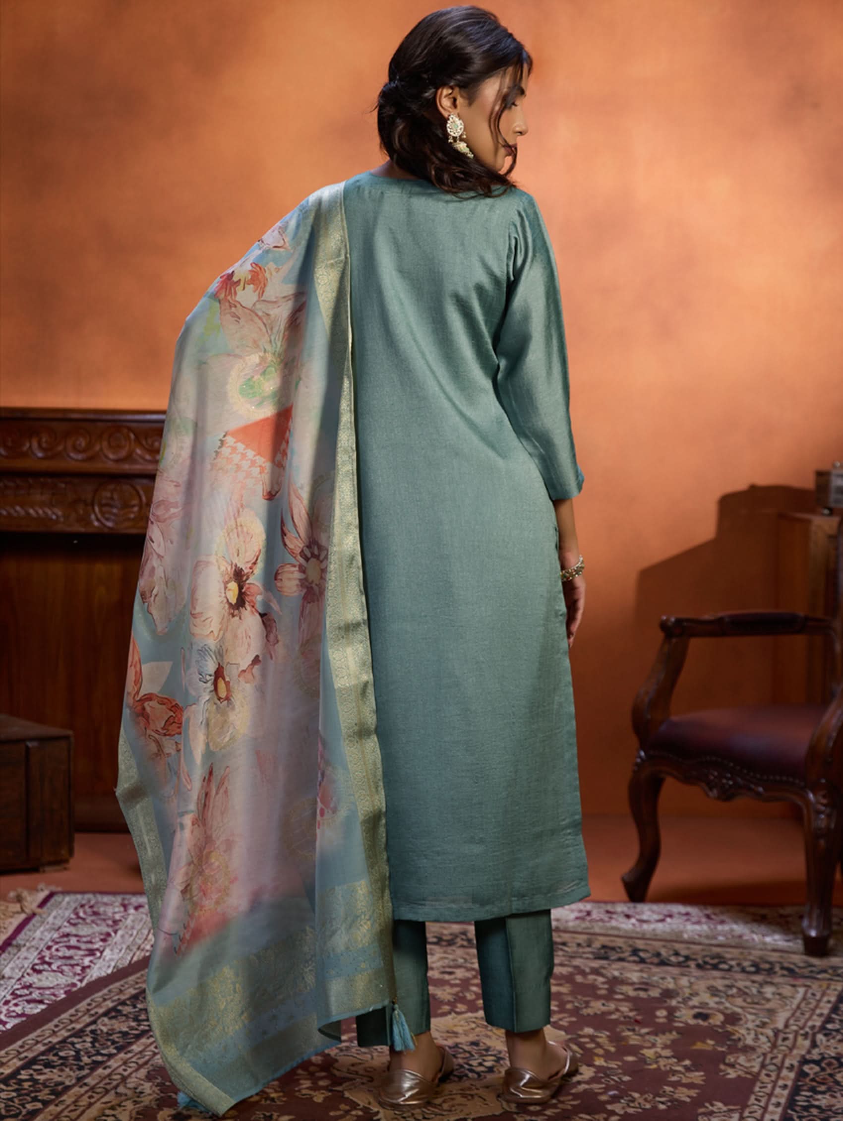 A woman wearing a blue suit set with embroidery, consisting of a kurta, pants, and a dupatta.