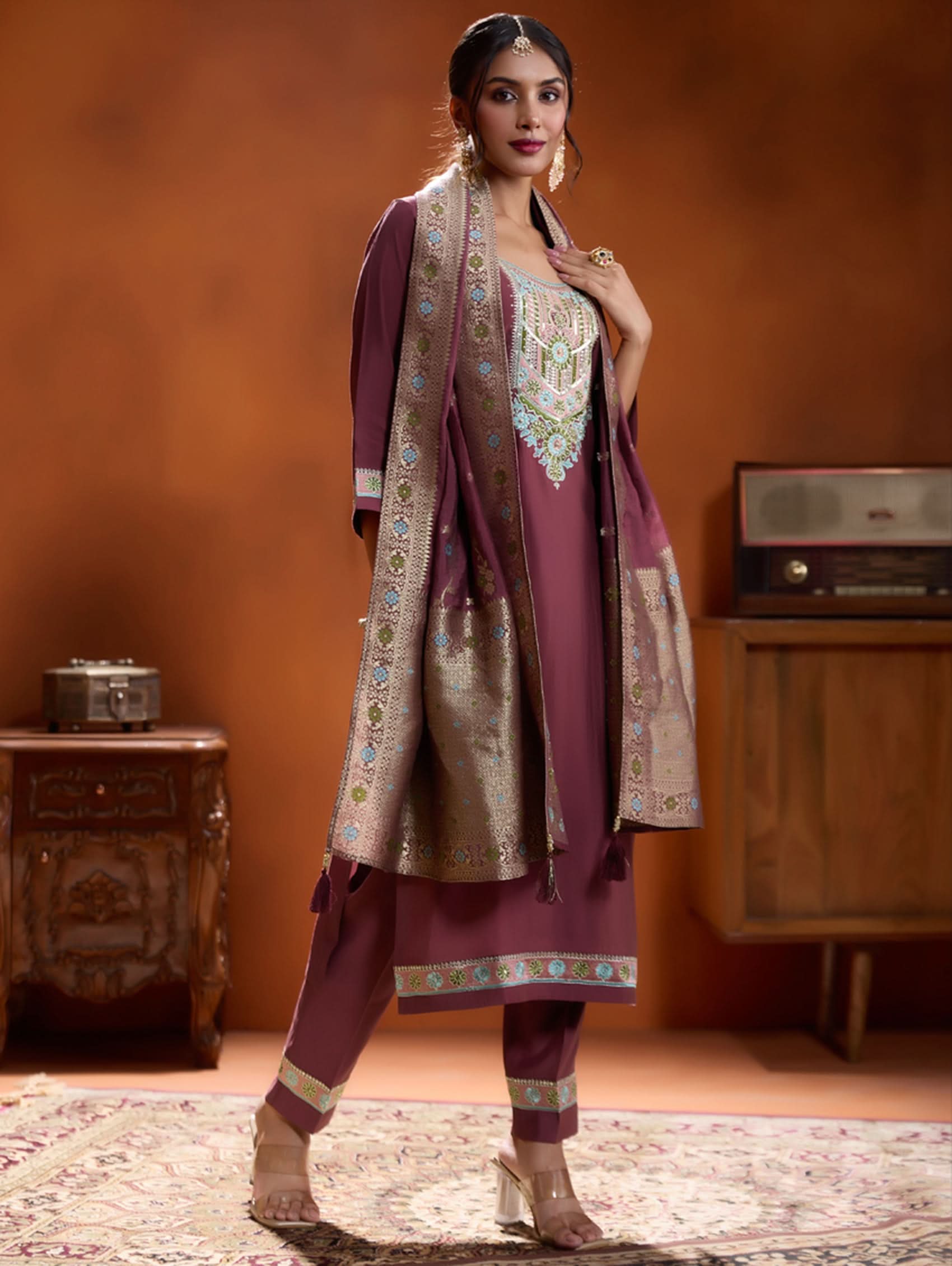 A woman modeling a maroon embroidered viscose silk suit set with a round neckline, three-fourth sleeves, and a dupatta. The set features cording thread embroidery along with hand embroidery.