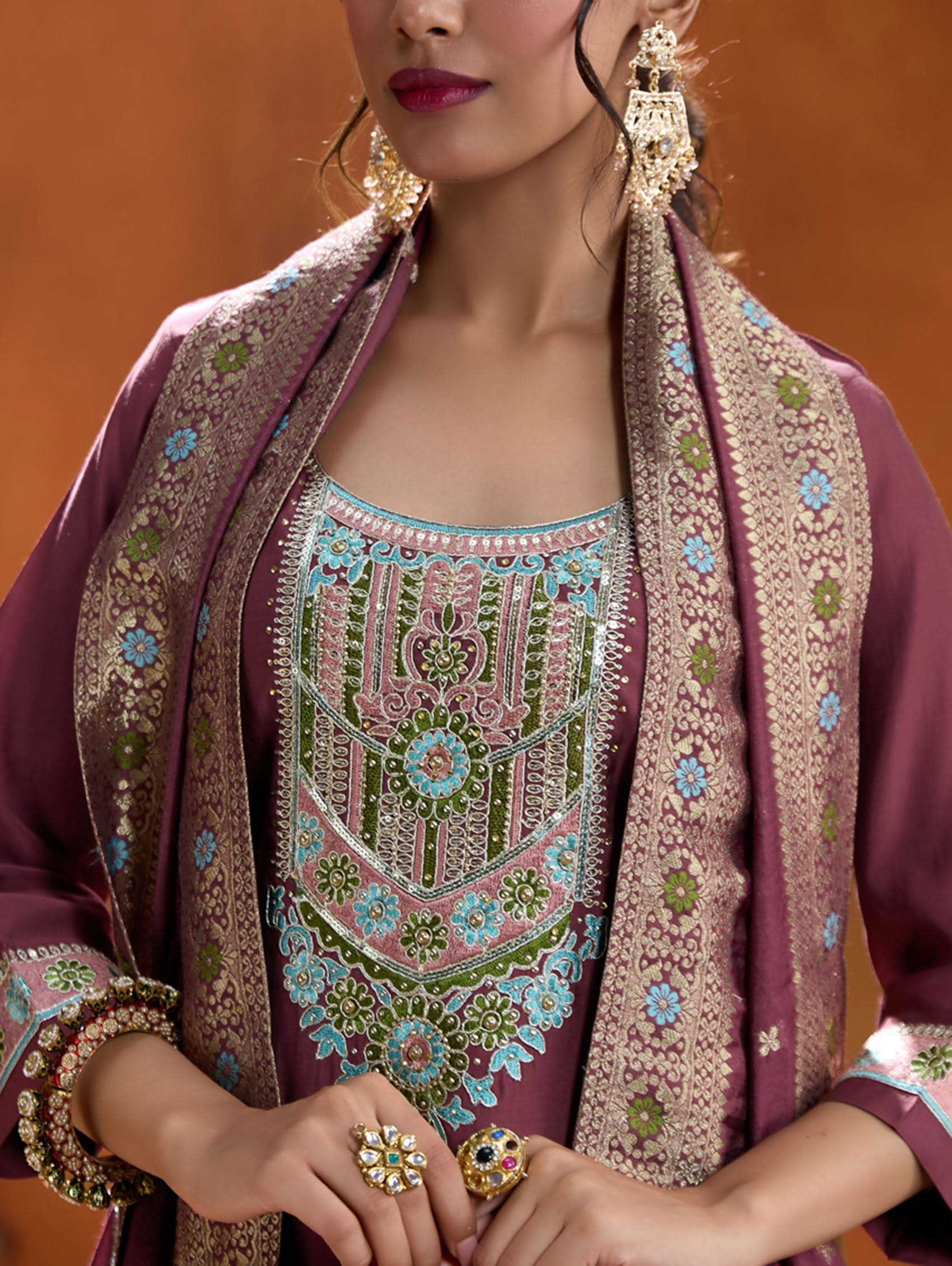 A woman modeling a maroon embroidered viscose silk suit set with a round neckline, three-fourth sleeves, and a dupatta. The set features cording thread embroidery along with hand embroidery.