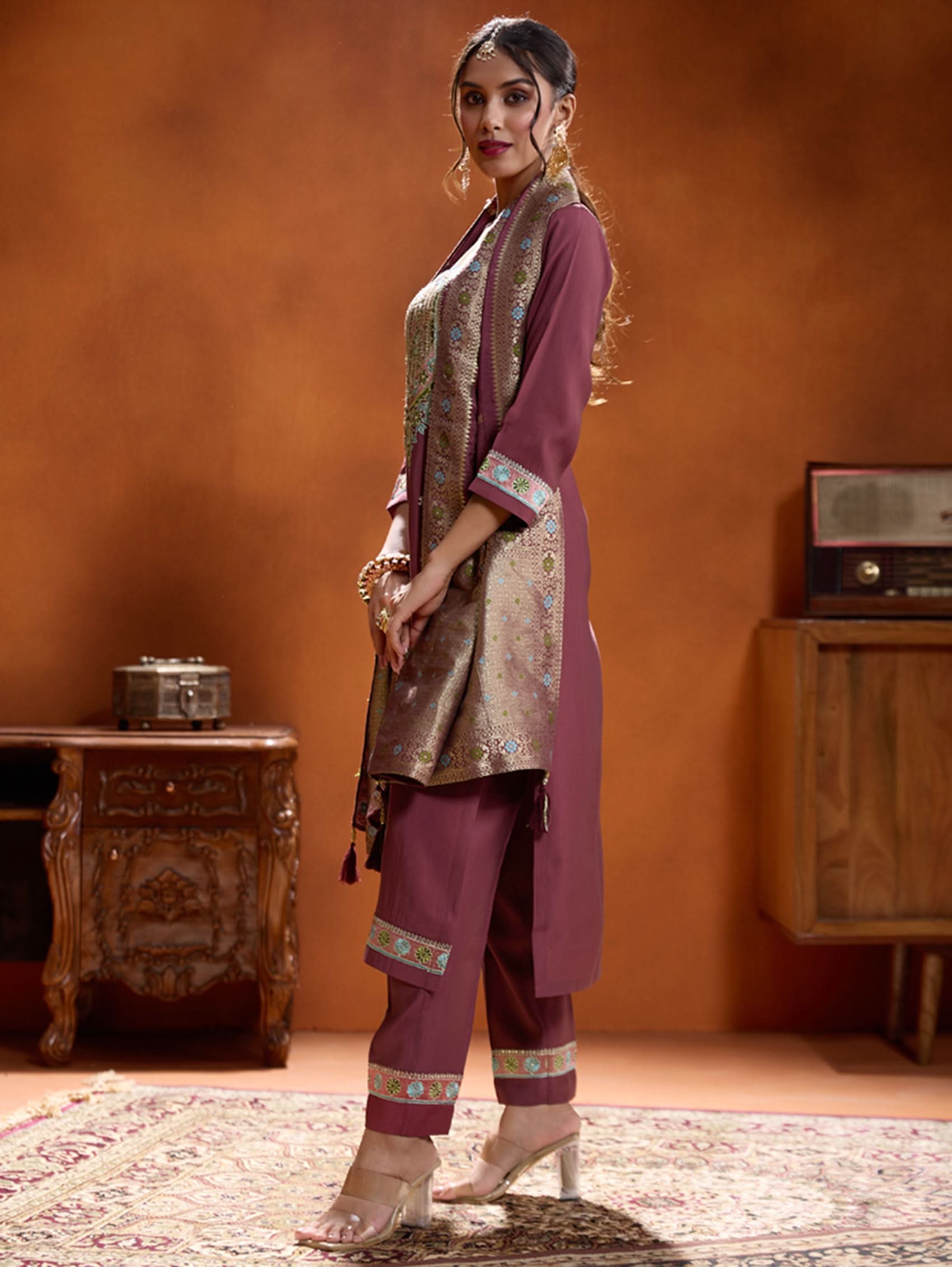 A woman modeling a maroon embroidered viscose silk suit set with a round neckline, three-fourth sleeves, and a dupatta. The set features cording thread embroidery along with hand embroidery.