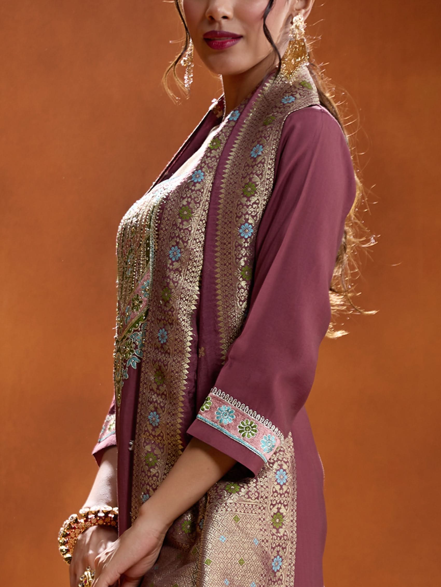 A woman modeling a maroon embroidered viscose silk suit set with a round neckline, three-fourth sleeves, and a dupatta. The set features cording thread embroidery along with hand embroidery.