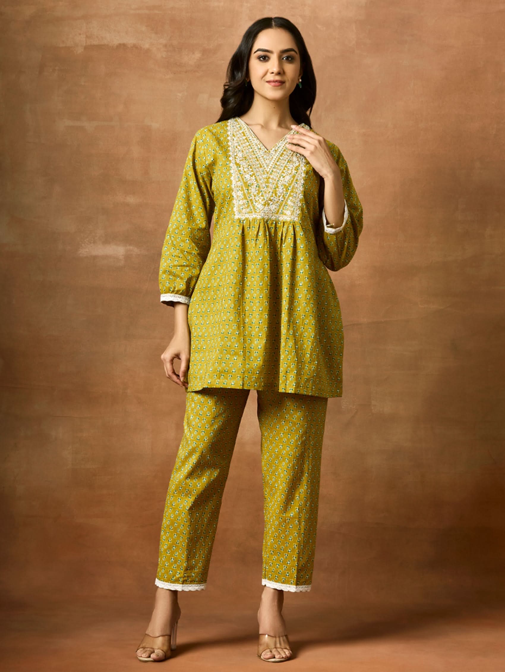 A model wearing a green pure cotton kurta with short sleeves and V-neckline, paired with matching pants, showcasing computerised thread embroidery.