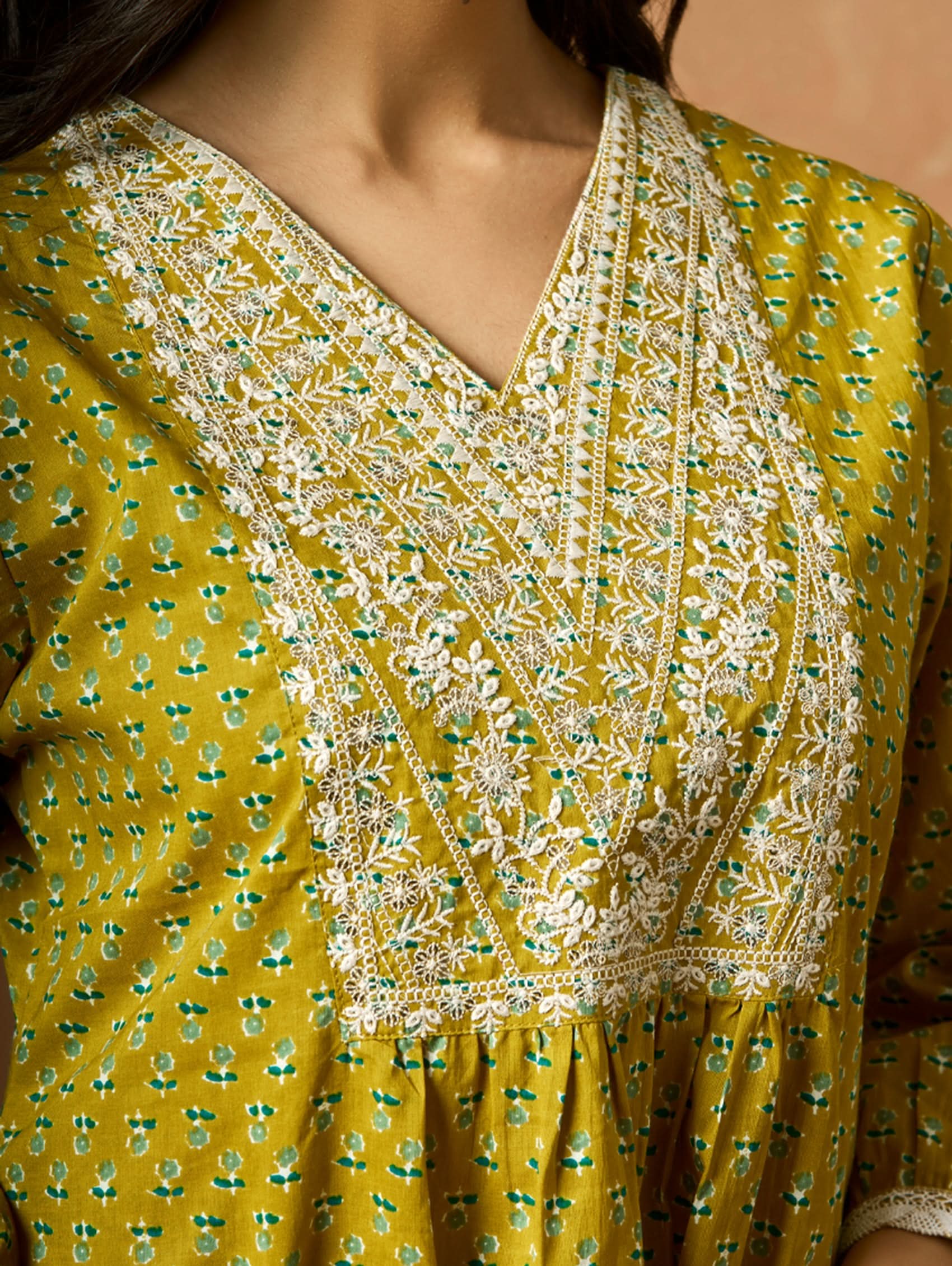A model wearing a green pure cotton kurta with short sleeves and V-neckline, paired with matching pants, showcasing computerised thread embroidery.