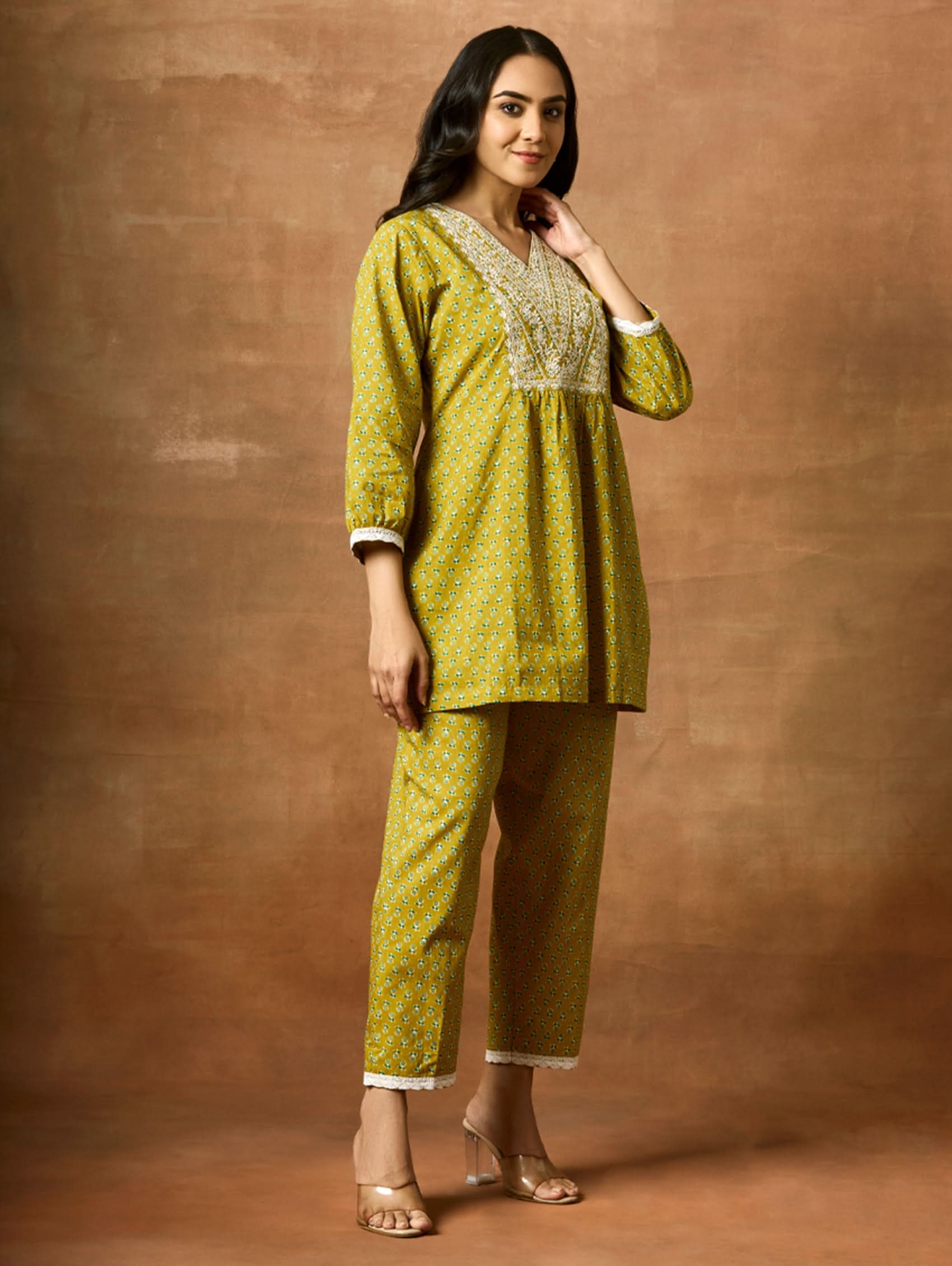 A model wearing a green pure cotton kurta with short sleeves and V-neckline, paired with matching pants, showcasing computerised thread embroidery.