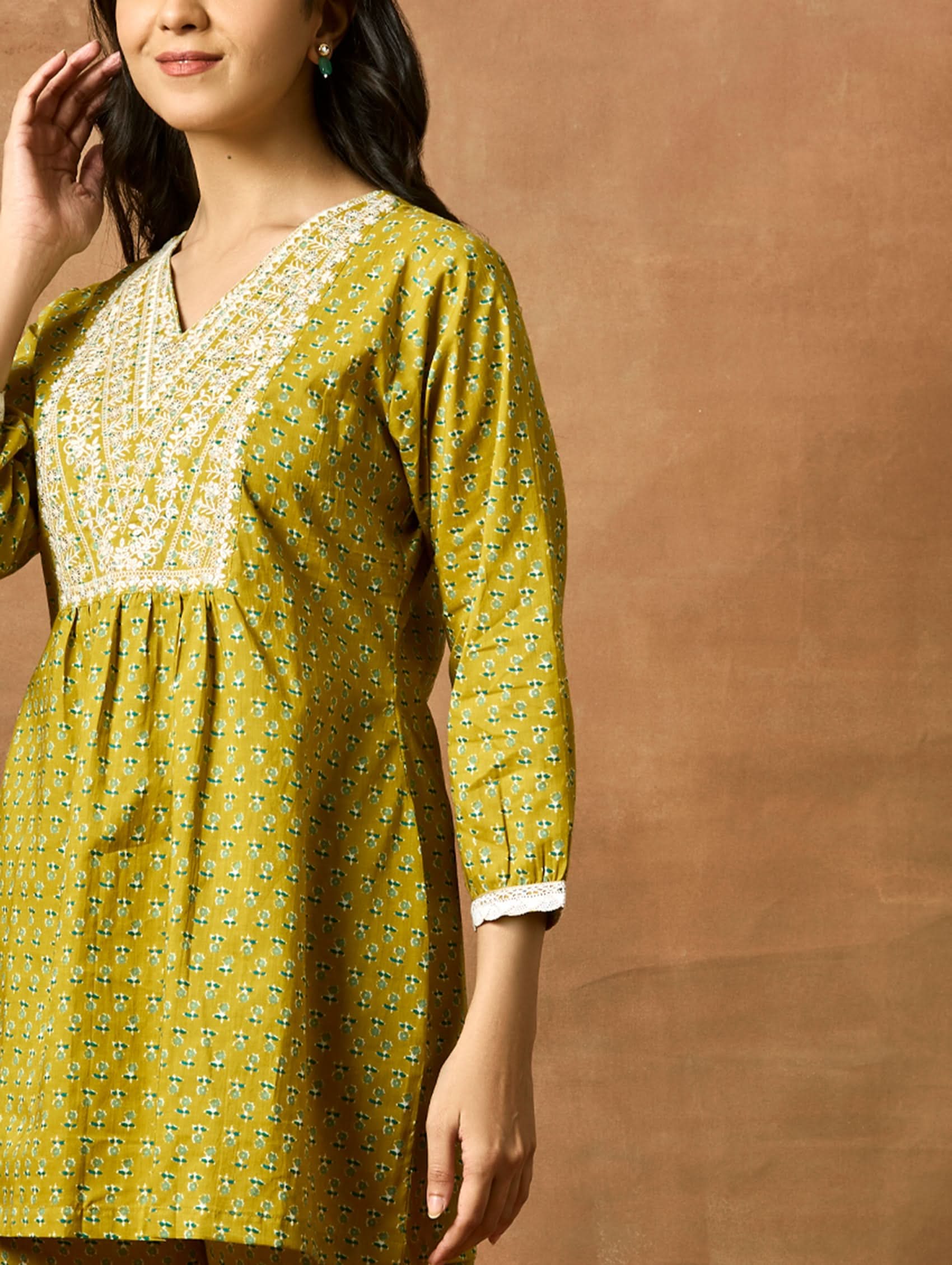 A model wearing a green pure cotton kurta with short sleeves and V-neckline, paired with matching pants, showcasing computerised thread embroidery.