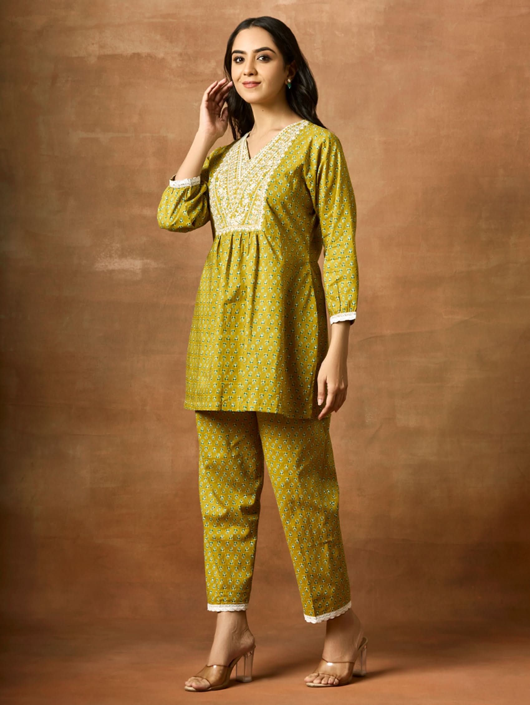 A model wearing a green pure cotton kurta with short sleeves and V-neckline, paired with matching pants, showcasing computerised thread embroidery.