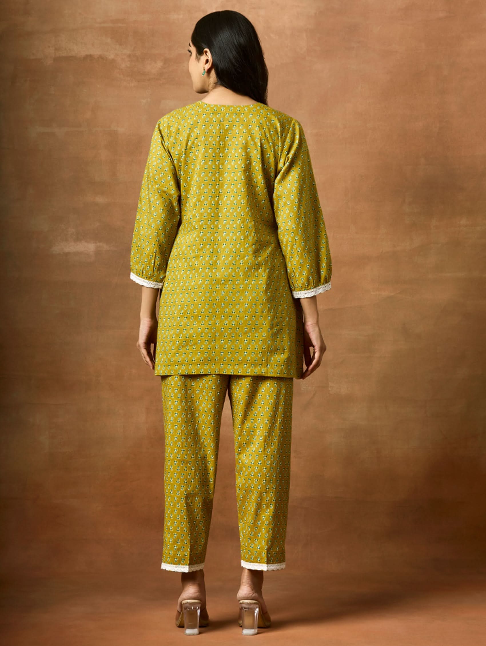 A model wearing a green pure cotton kurta with short sleeves and V-neckline, paired with matching pants, showcasing computerised thread embroidery.