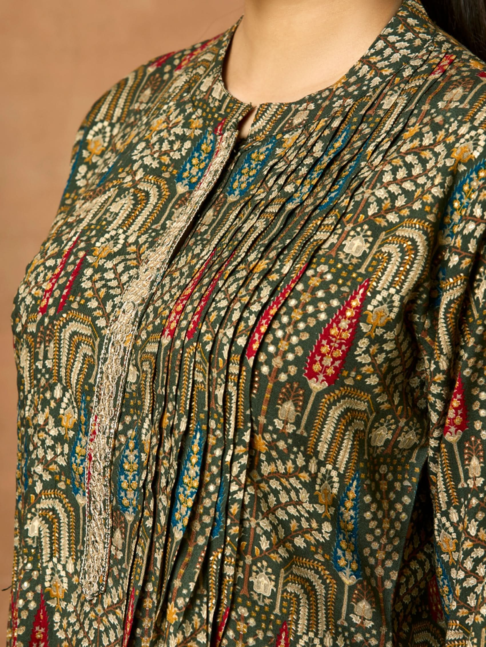 A woman modeling a green and orange floral printed viscose rayon co-ord set with a mandarin collar and three-fourth sleeves kurta, and matching pants with a partially elasticated waistband and side pockets.