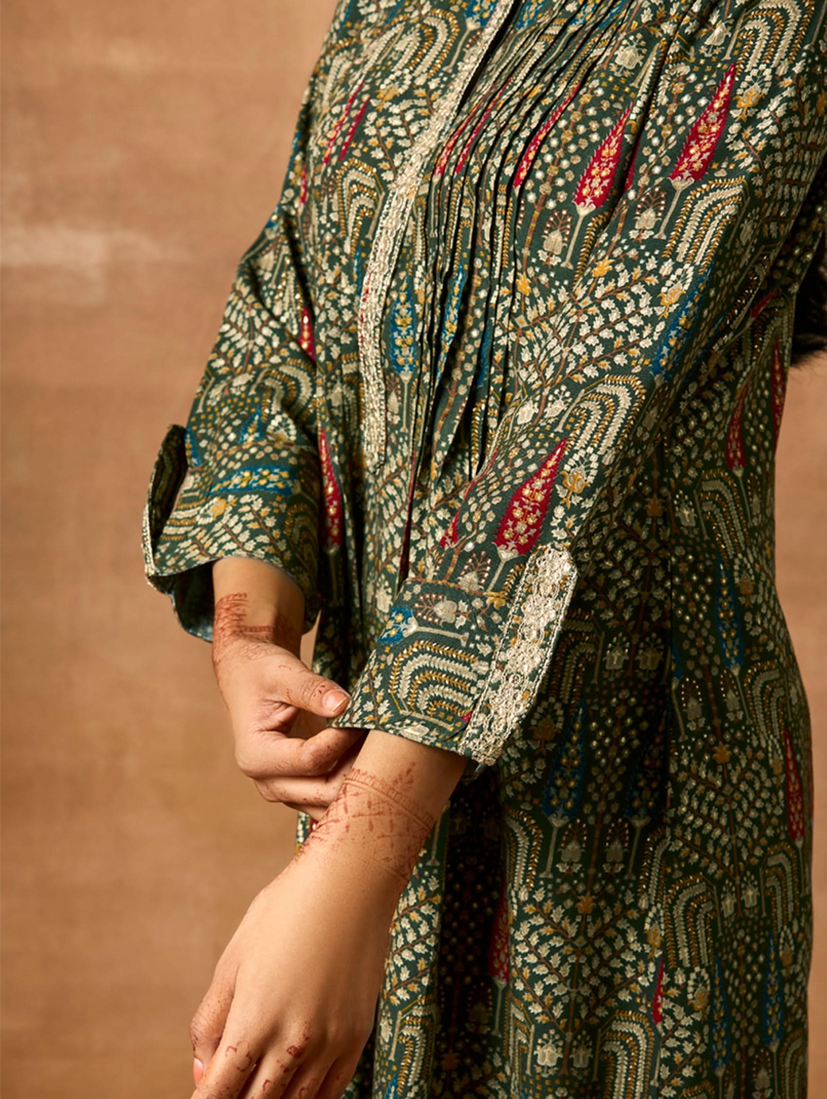 A woman modeling a green and orange floral printed viscose rayon co-ord set with a mandarin collar and three-fourth sleeves kurta, and matching pants with a partially elasticated waistband and side pockets.