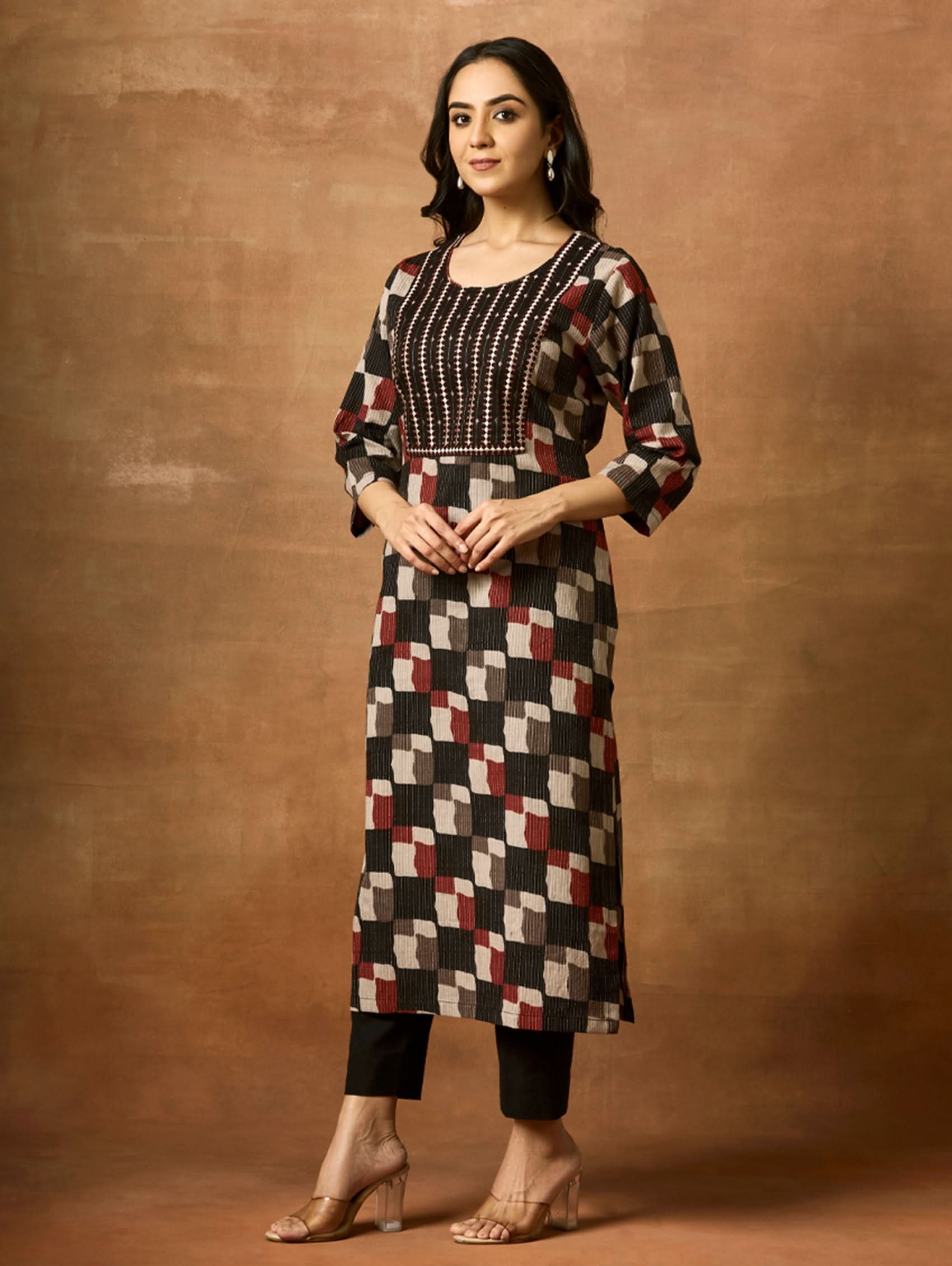 Woman wearing a patterned kurta and pants against a brown background