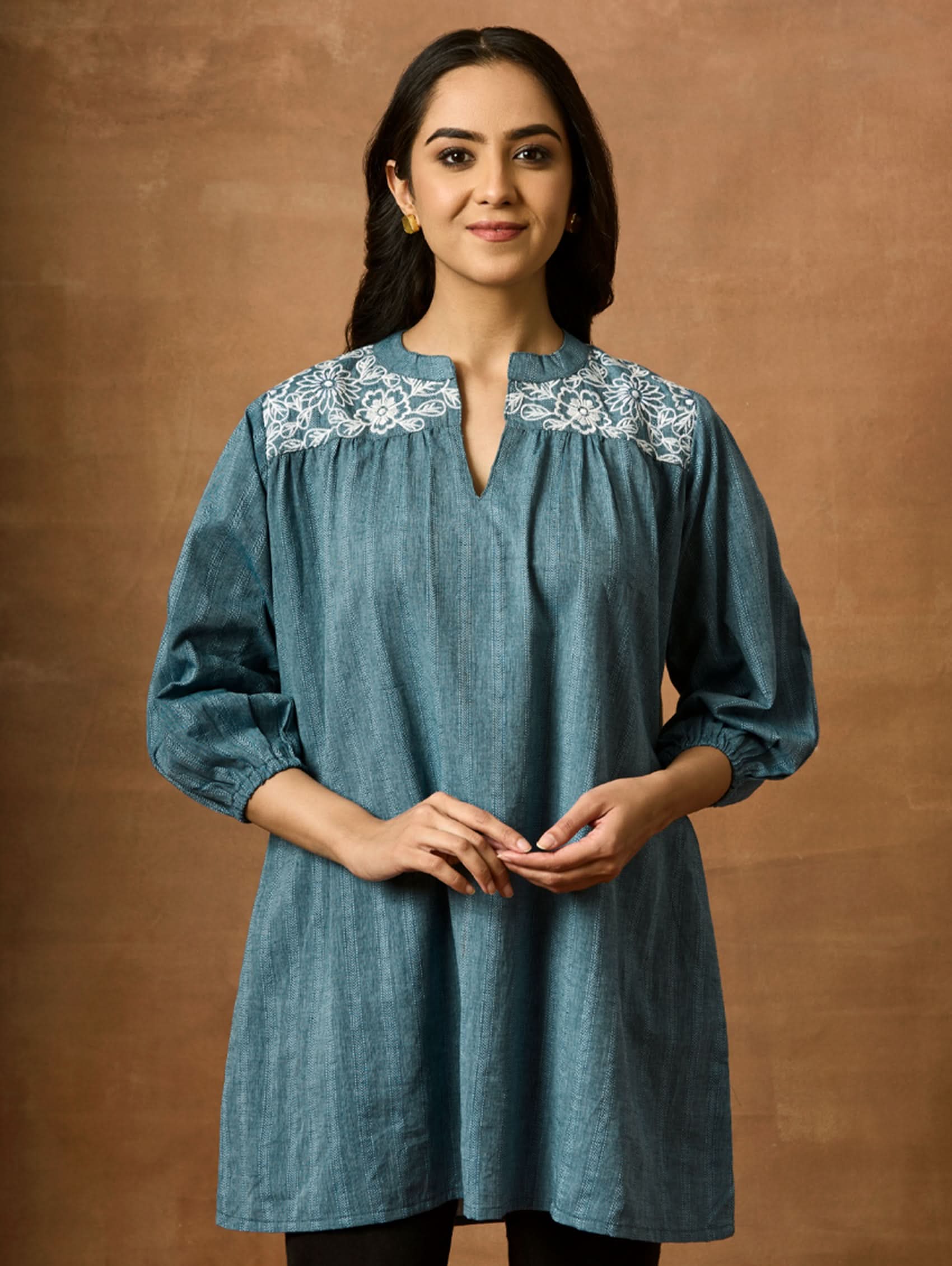 A woman wearing a blue pure cotton tunic with a Band collar and three-quarter sleeves, featuring computerised thread embroidery.