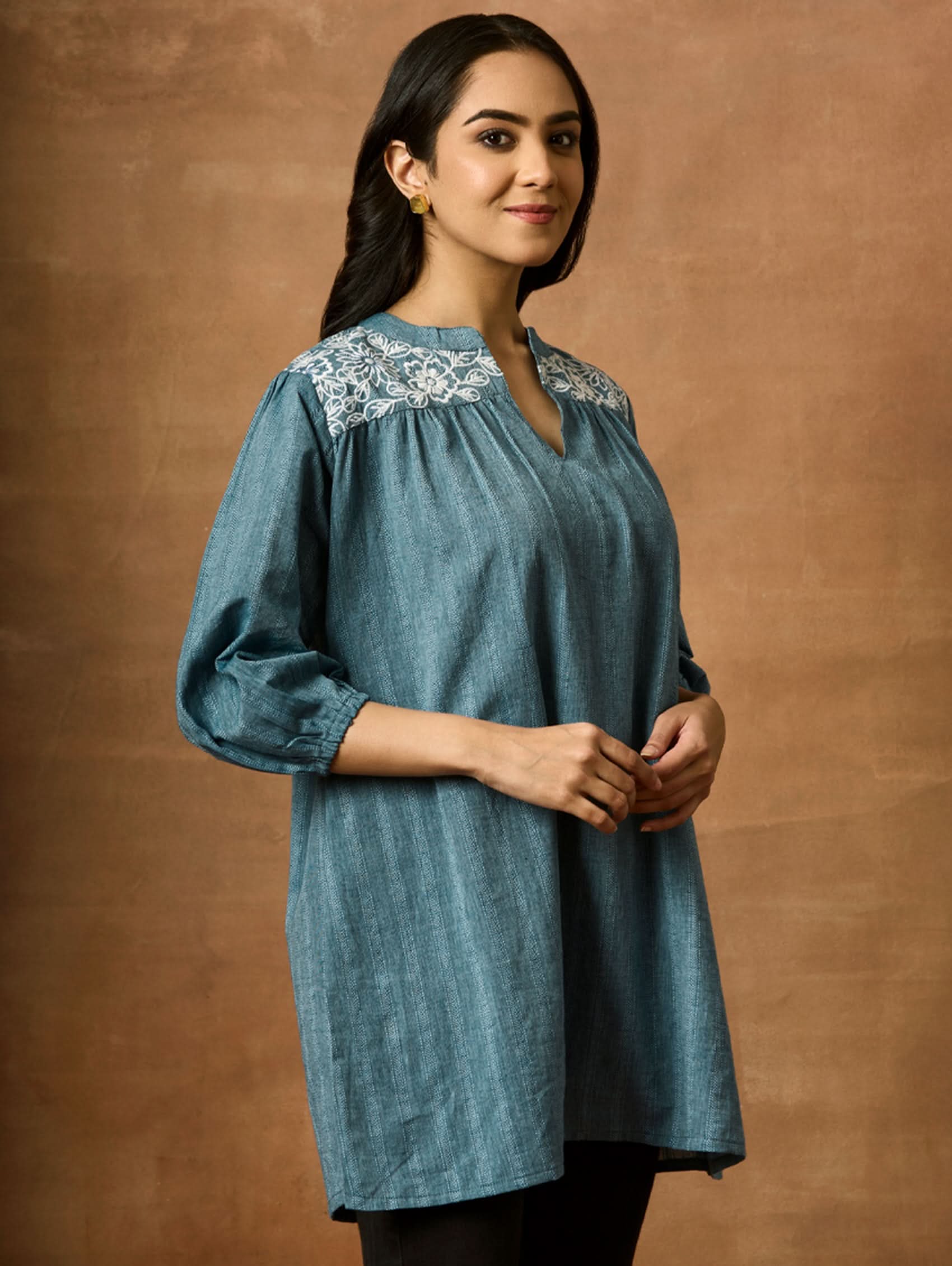 A woman wearing a blue pure cotton tunic with a Band collar and three-quarter sleeves, featuring computerised thread embroidery.