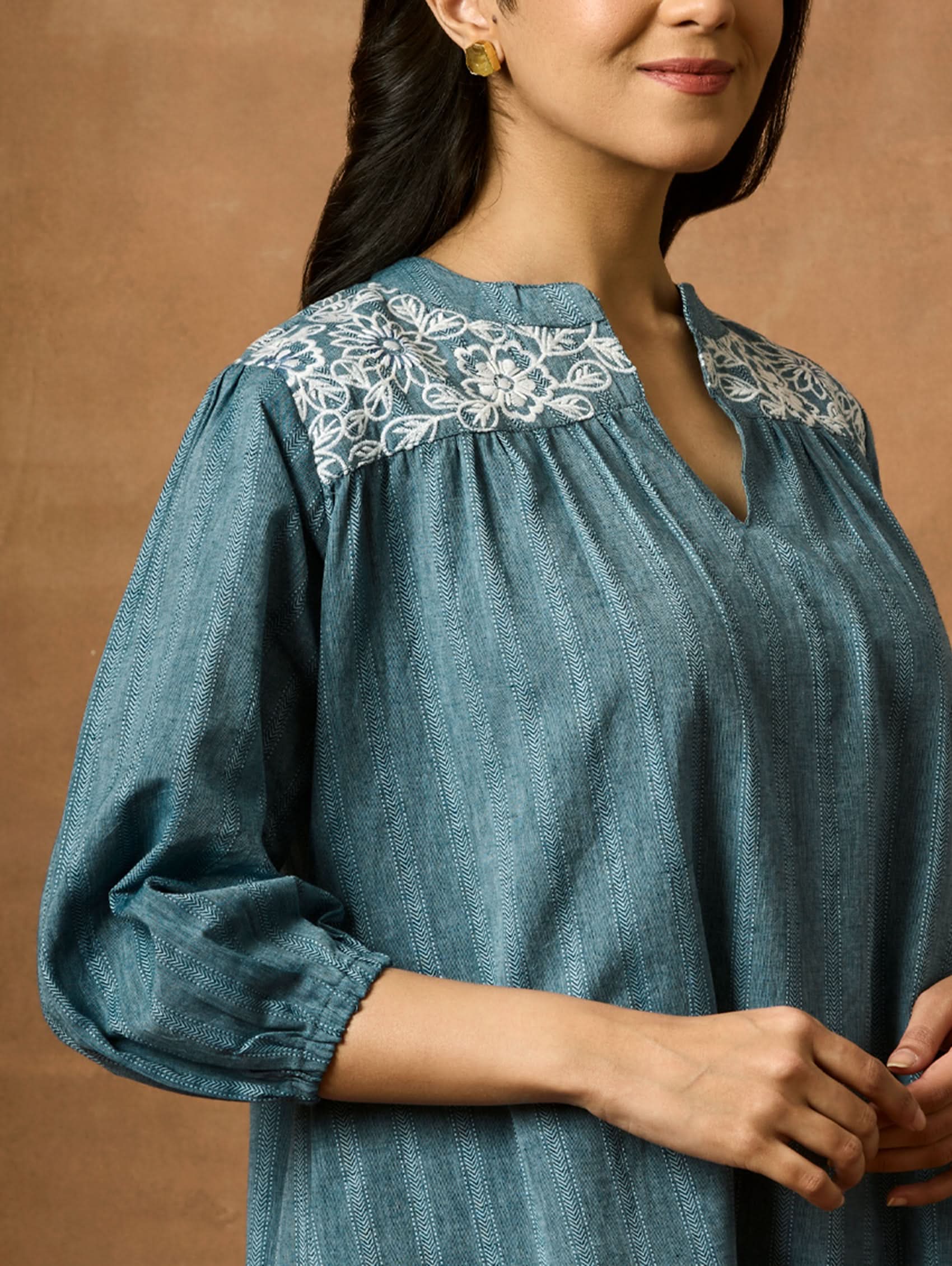 A woman wearing a blue pure cotton tunic with a Band collar and three-quarter sleeves, featuring computerised thread embroidery.