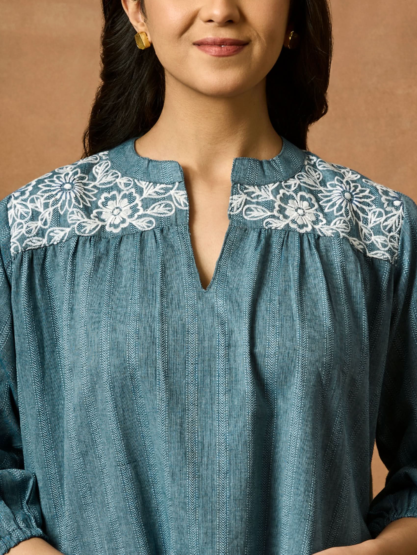 A woman wearing a blue pure cotton tunic with a Band collar and three-quarter sleeves, featuring computerised thread embroidery.