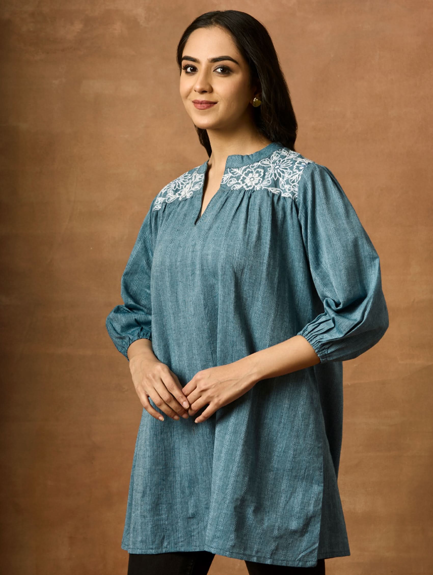 A woman wearing a blue pure cotton tunic with a Band collar and three-quarter sleeves, featuring computerised thread embroidery.