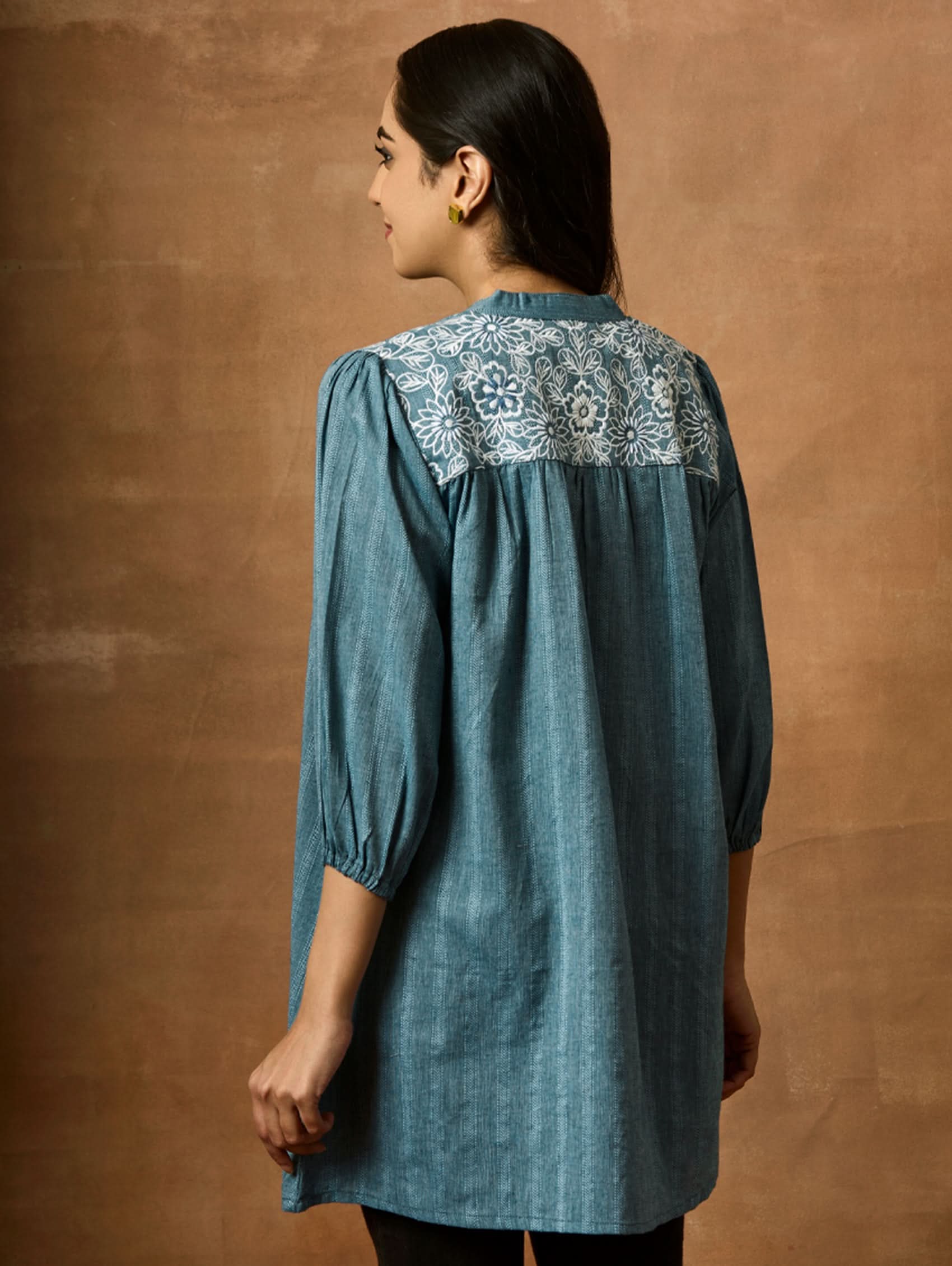 A woman wearing a blue pure cotton tunic with a Band collar and three-quarter sleeves, featuring computerised thread embroidery.
