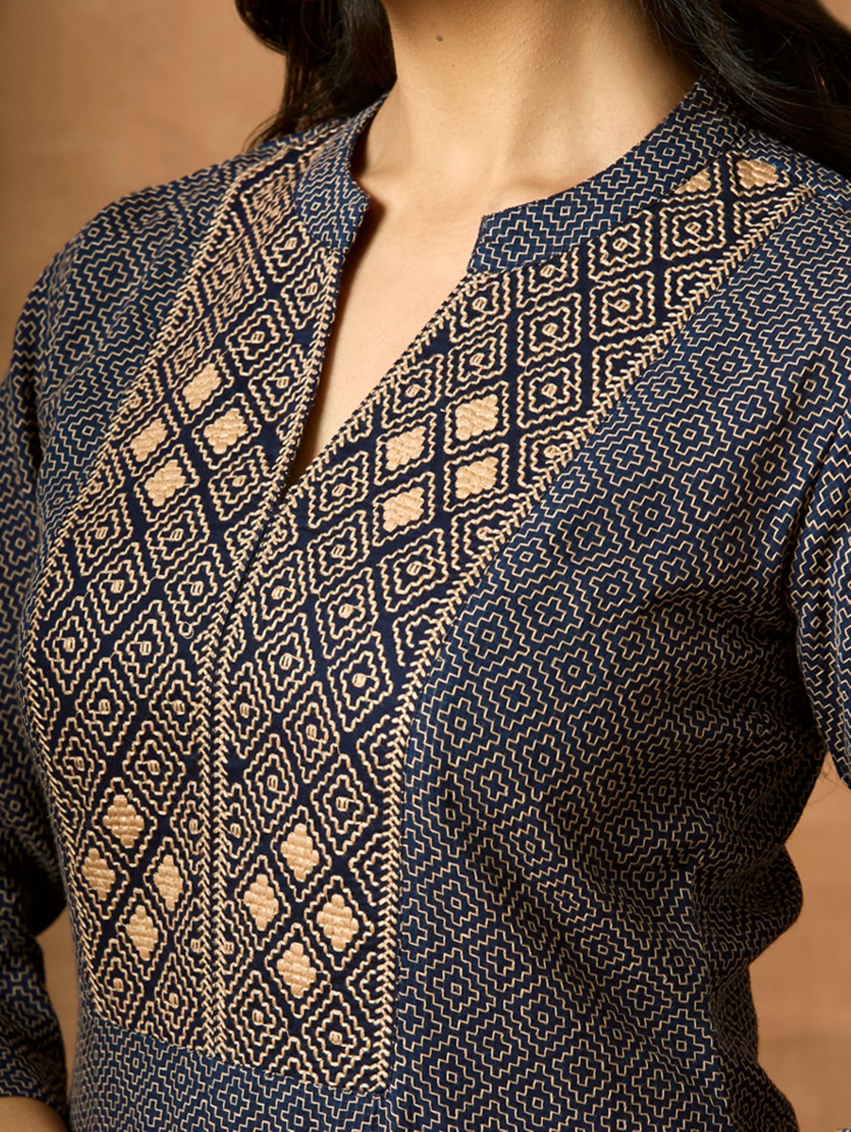 Embroidered cotton kurta close-up of geometric motif with gold-toned and dark stitching