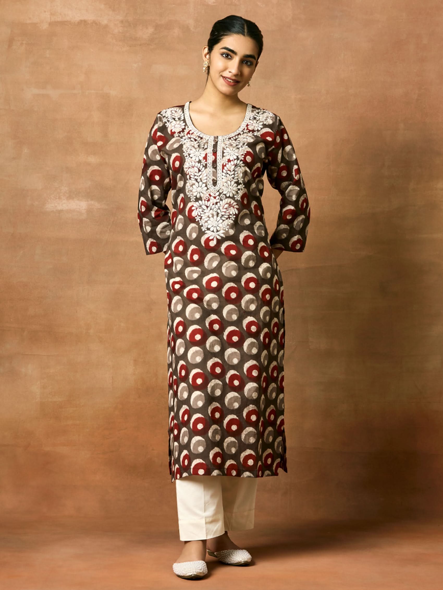 A woman plus size model wearing a printed pure cotton kurta with round neckline, three-fourth sleeves, and side slits. The kurta is predominantly in shades of pink and white with embroidered details.