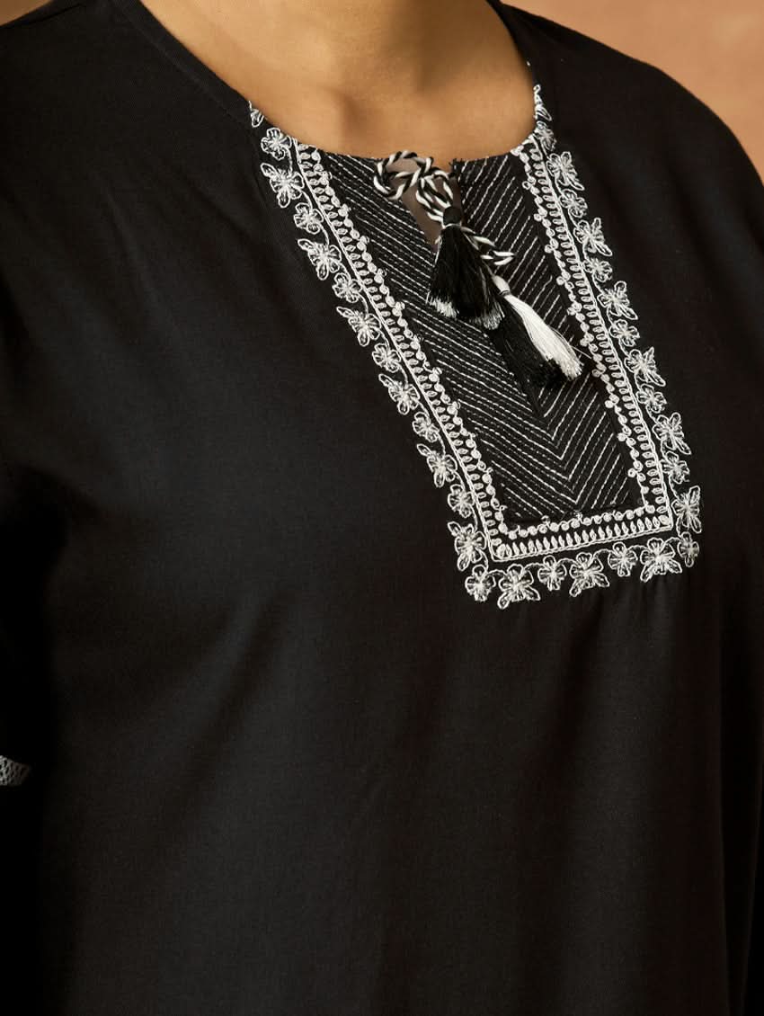 Black garment with intricate white embroidery on the neckline.