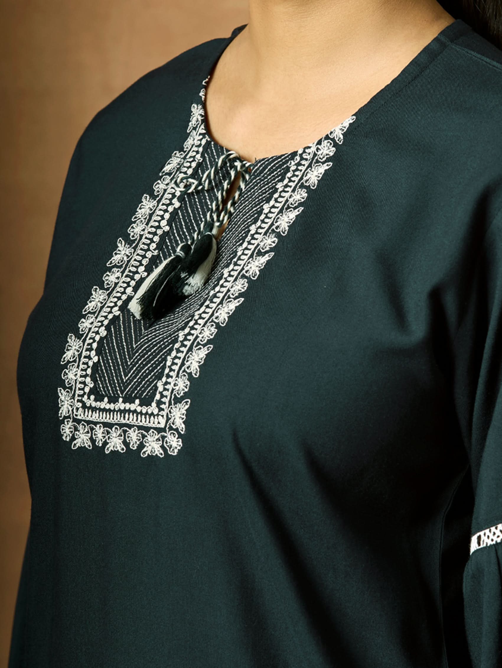 Dark green garment with intricate white embroidery on the neckline.