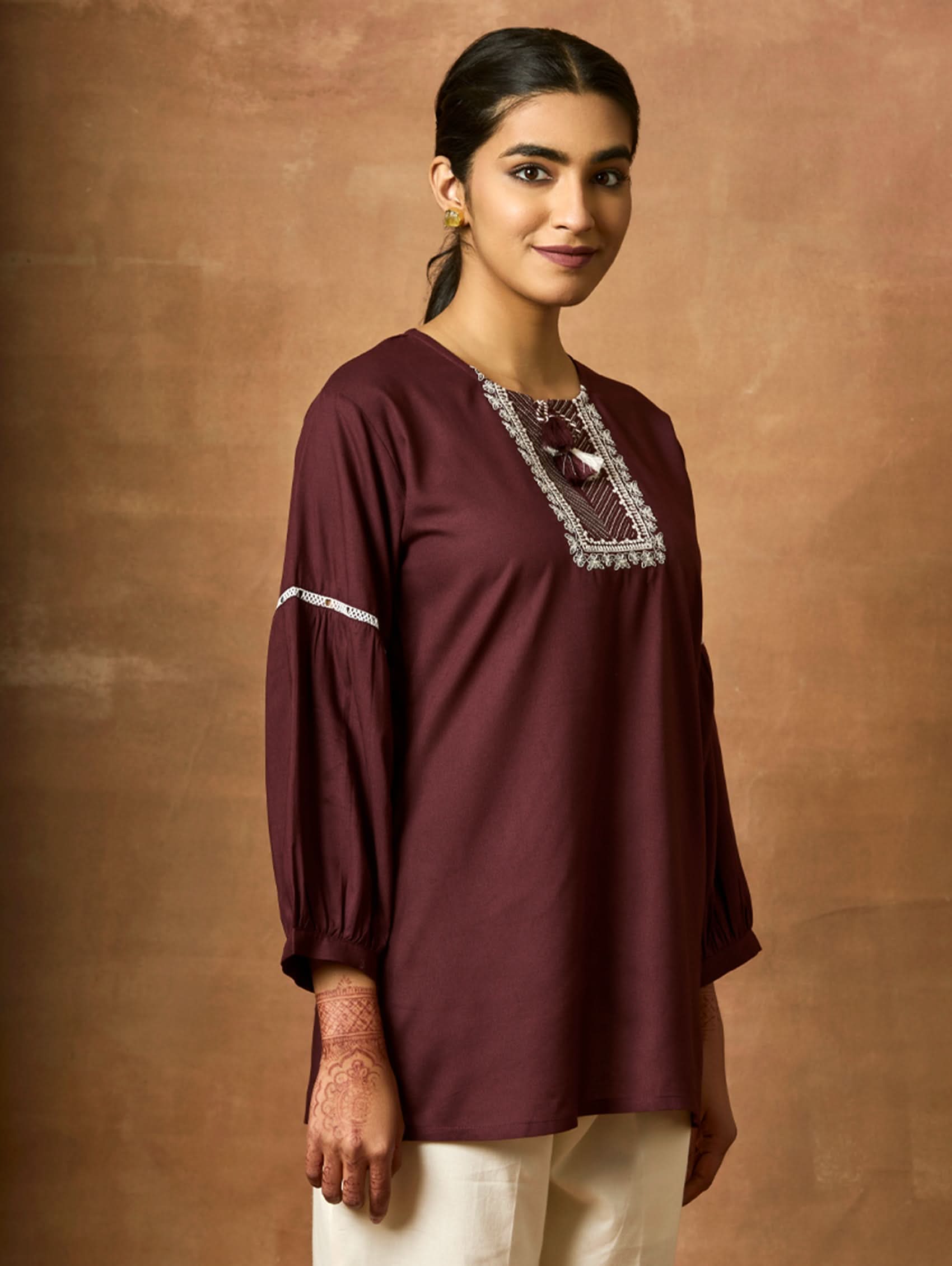 A woman wearing a black viscose rayon tunic with a round neckline, three-quarter sleeves, and computerised thread embroidery on the tunic.