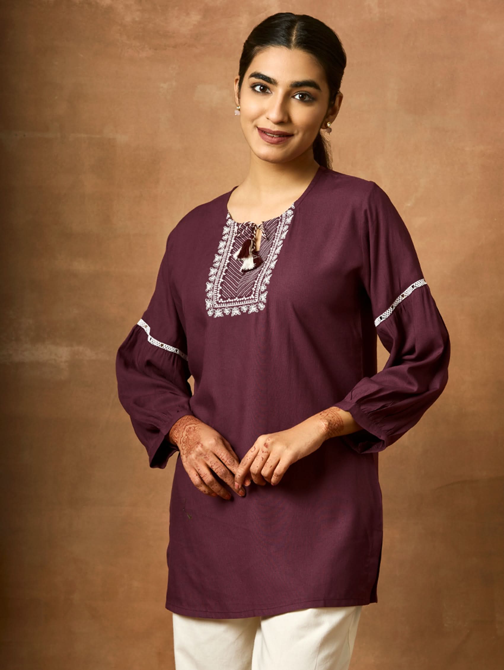 A woman wearing a black viscose rayon tunic with a round neckline, three-quarter sleeves, and computerised thread embroidery on the tunic.