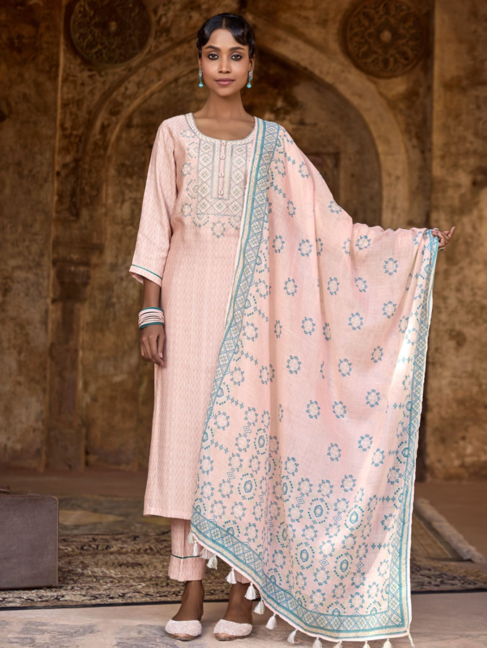 A woman wearing a checkered silk suit set with embroidered details,and embroidered consisting of a kurta with band collar, pants, and a embroidered weave silk dupatta.