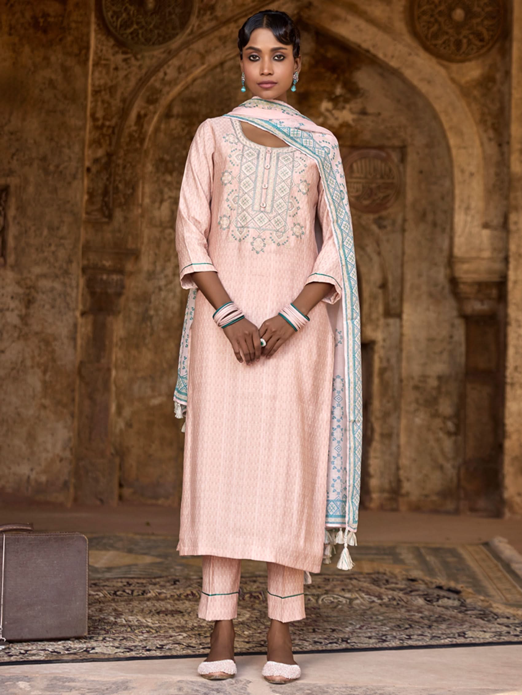 A woman wearing a checkered silk suit set with embroidered details,and embroidered consisting of a kurta with band collar, pants, and a embroidered weave silk dupatta.