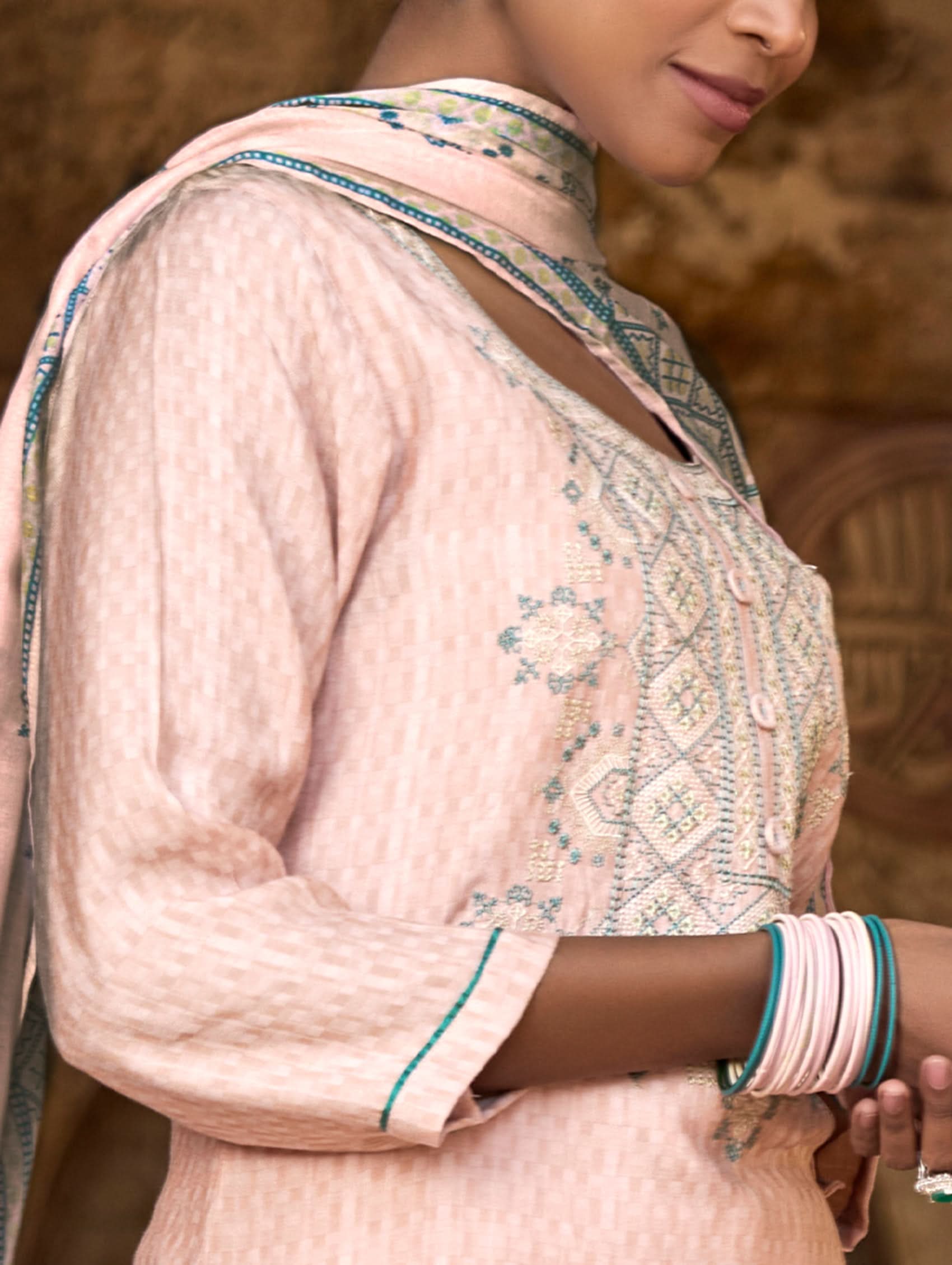 A woman wearing a checkered silk suit set with embroidered details,and embroidered consisting of a kurta with band collar, pants, and a embroidered weave silk dupatta.