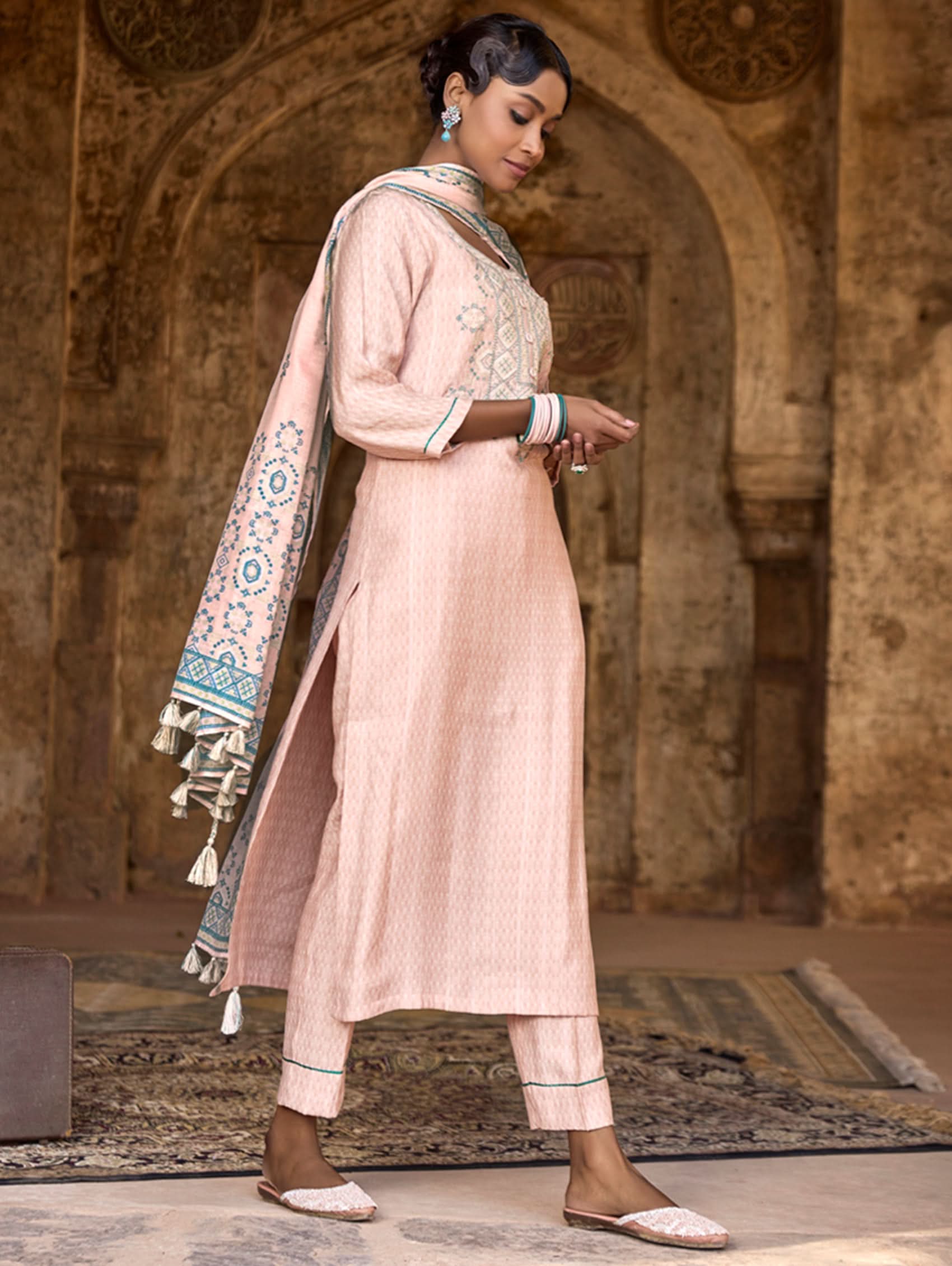 A woman wearing a checkered silk suit set with embroidered details,and embroidered consisting of a kurta with band collar, pants, and a embroidered weave silk dupatta.
