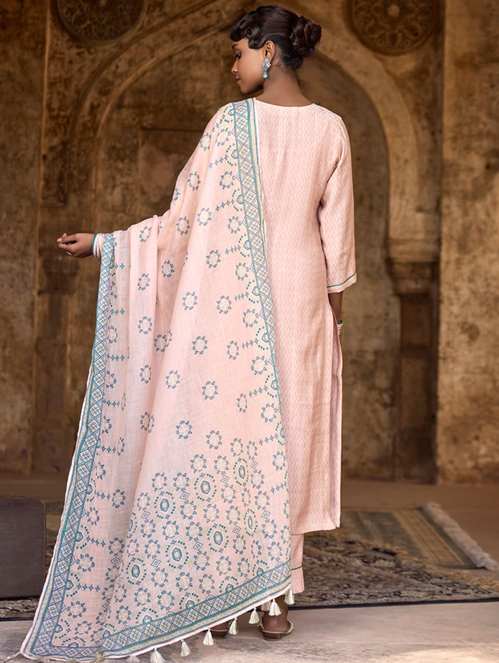 A woman wearing a checkered silk suit set with embroidered details,and embroidered consisting of a kurta with band collar, pants, and a embroidered weave silk dupatta.