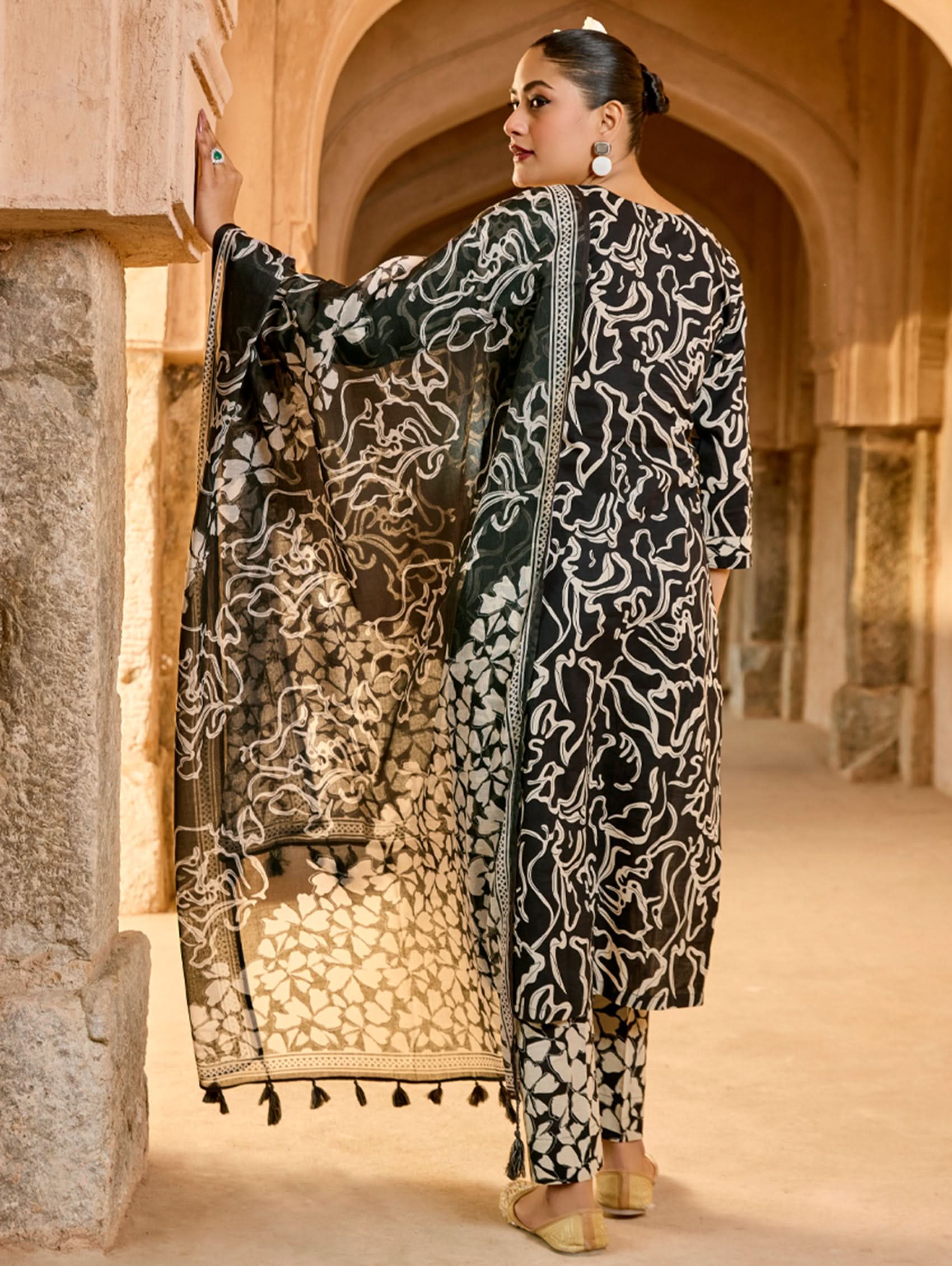 Person wearing a black and white patterned outfit in an archway.