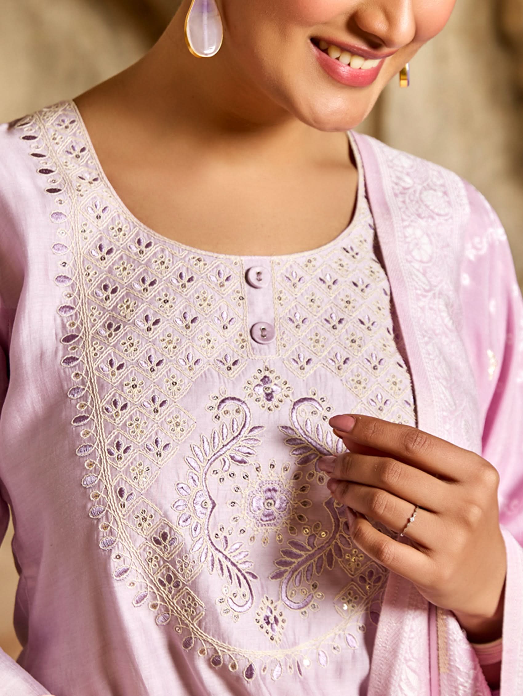 A woman wearing a pink viscose silk suit set with embroidered details, consisting of a kurta, pants, and a jacquard weave silk dupatta.