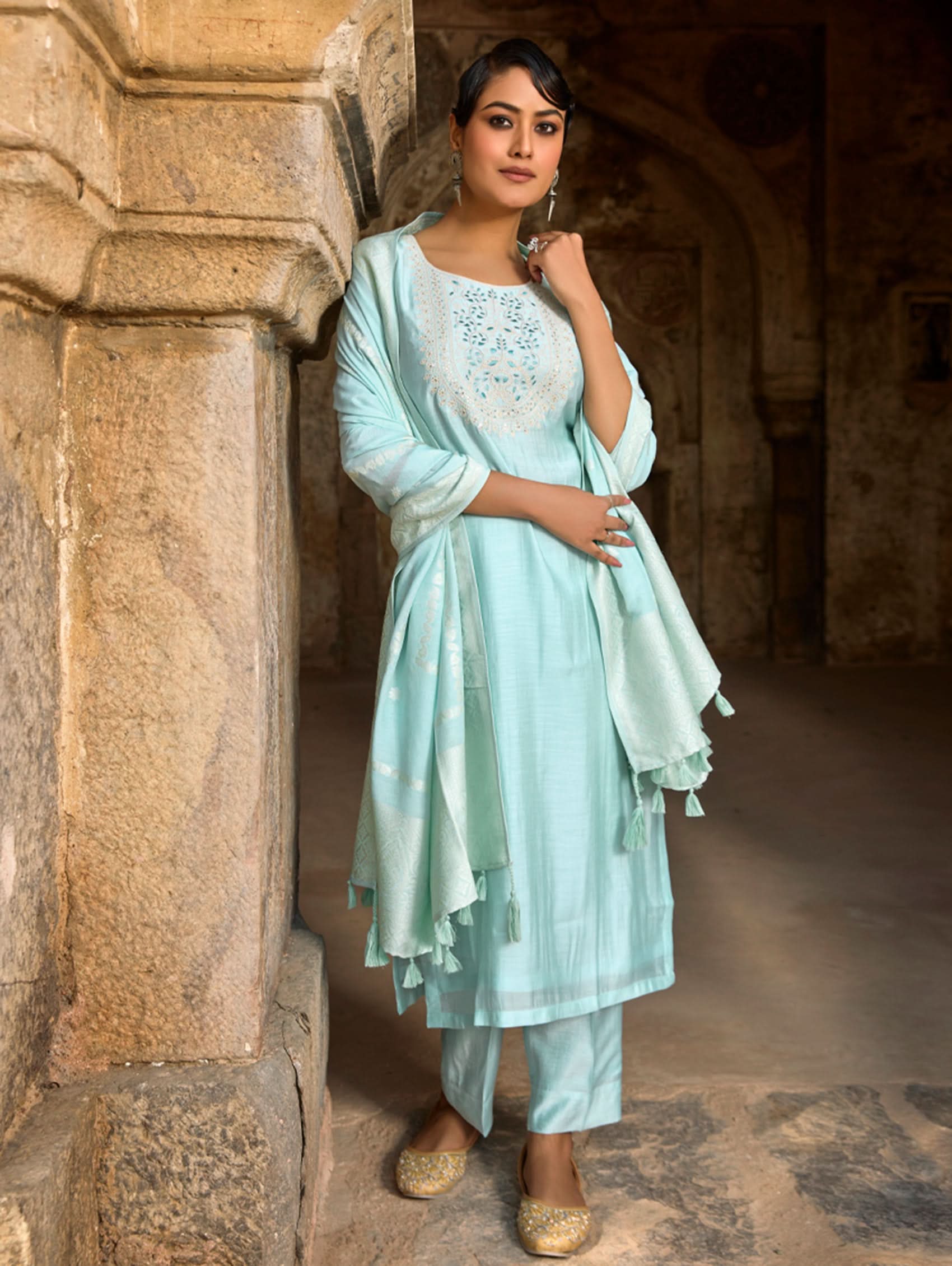 A woman wearing a light blue viscose silk suit set with embroidered details, consisting of a kurta, pants, and a dupatta.