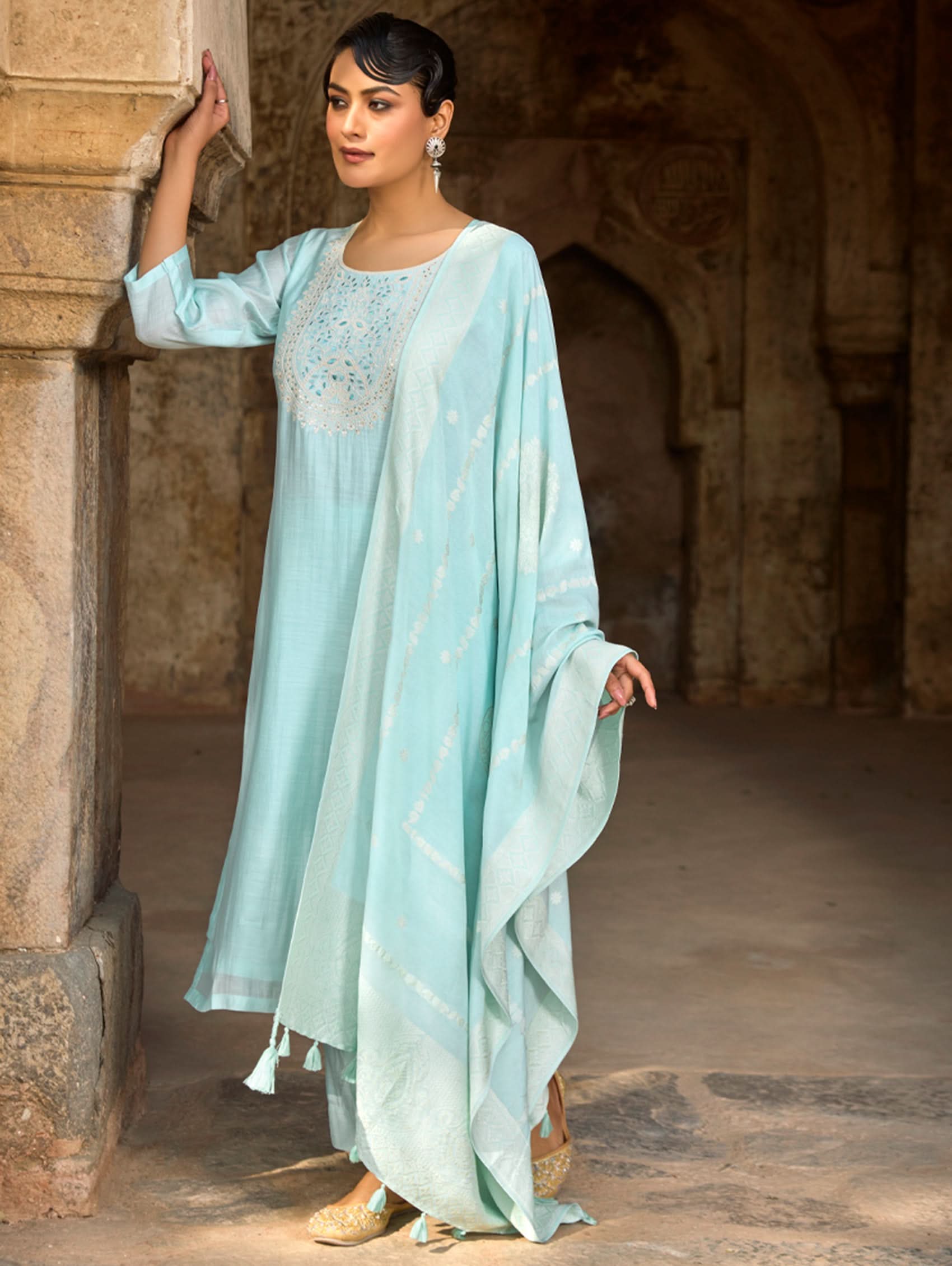 A woman wearing a light blue viscose silk suit set with embroidered details, consisting of a kurta, pants, and a dupatta.