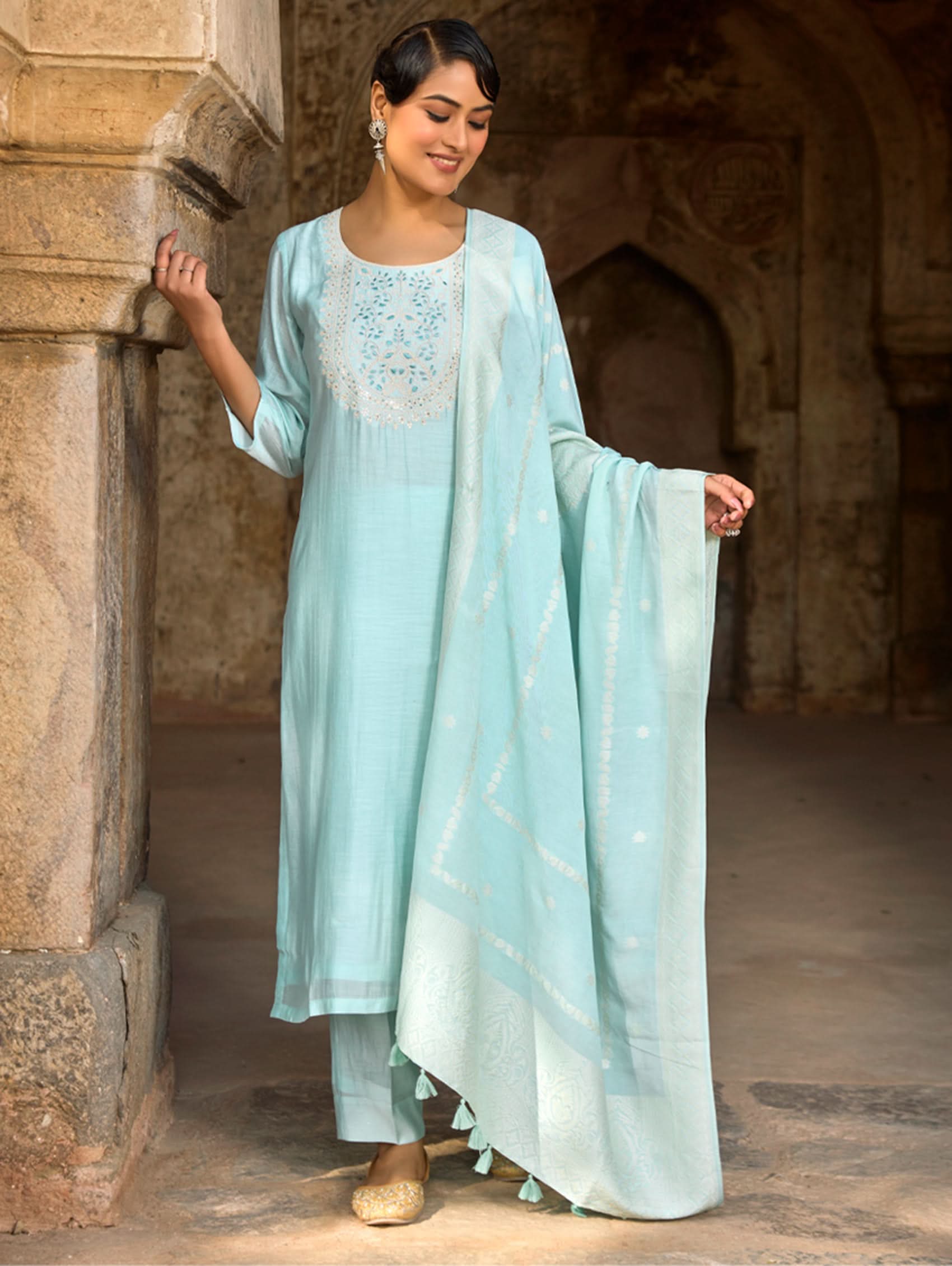 A woman wearing a light blue viscose silk suit set with embroidered details, consisting of a kurta, pants, and a dupatta.