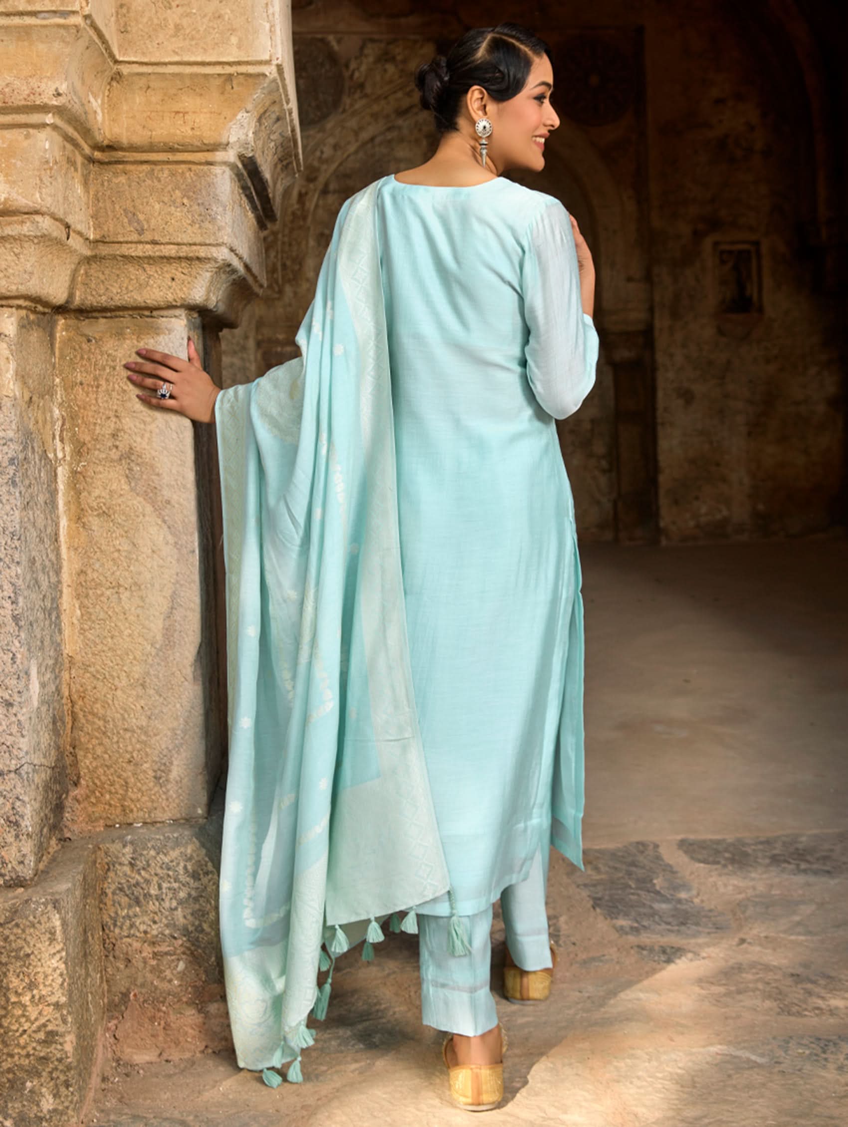 A woman wearing a light blue viscose silk suit set with embroidered details, consisting of a kurta, pants, and a dupatta.