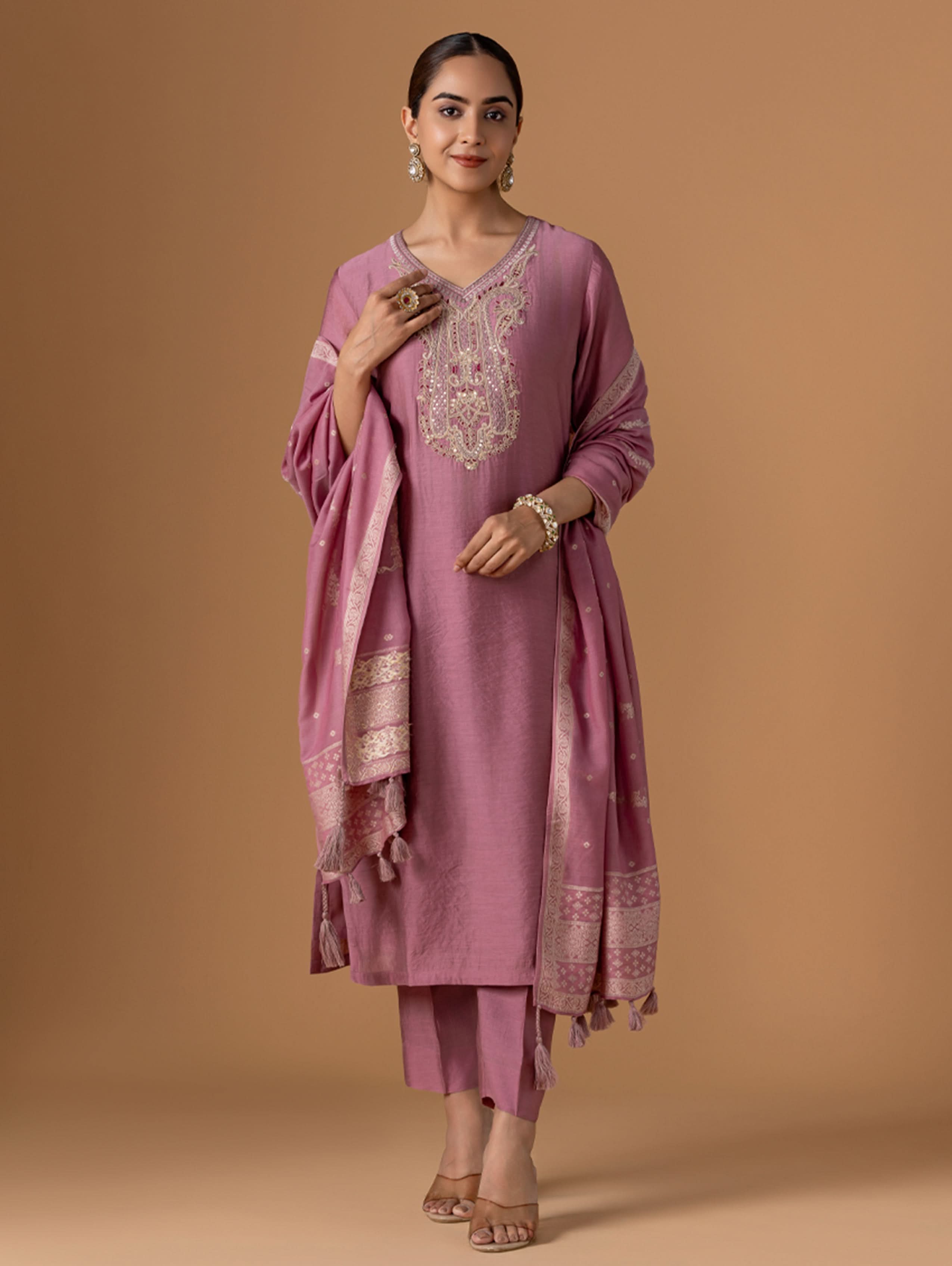 Woman wearing a pink traditional outfit with embroidery on a beige background
