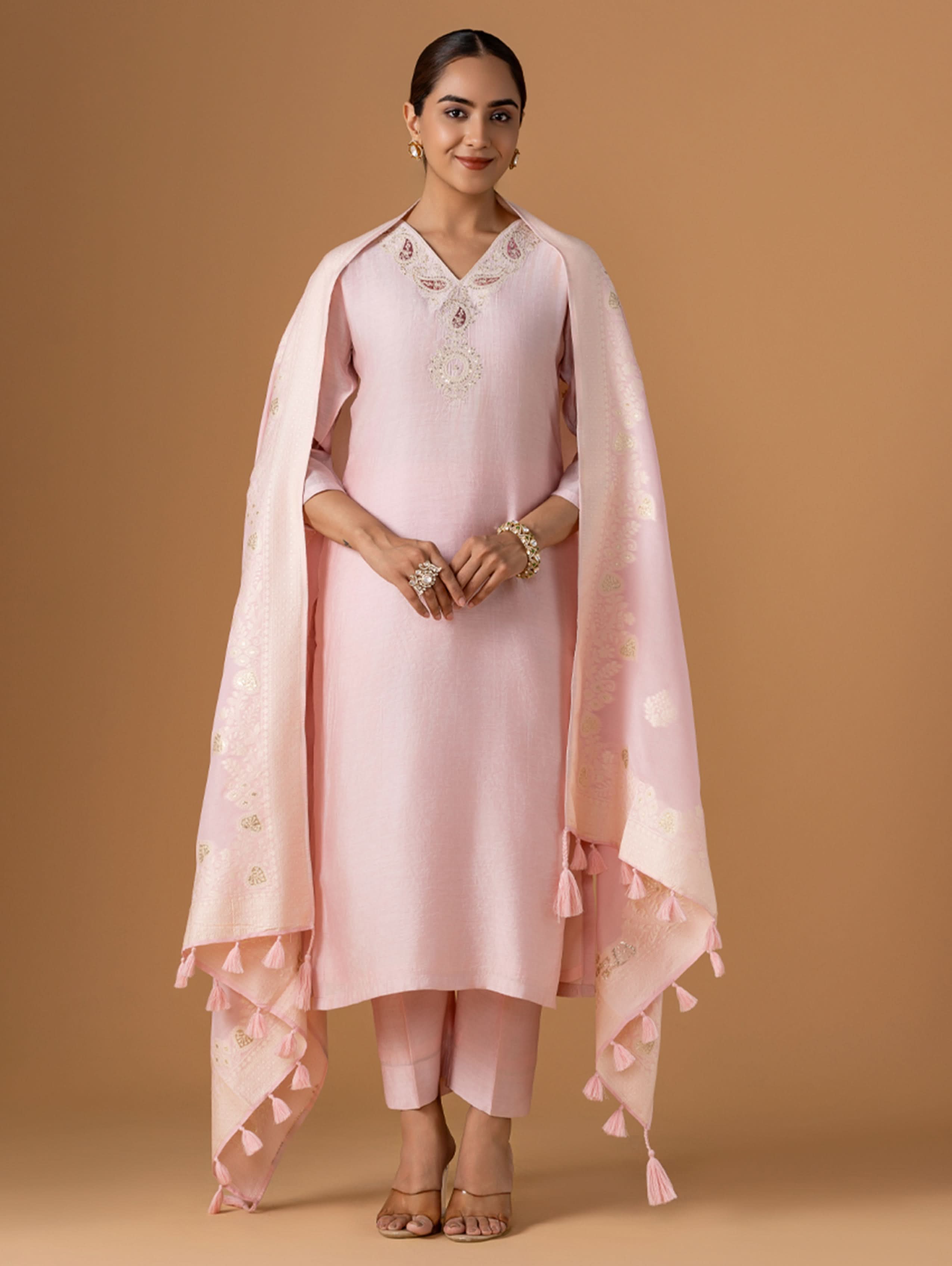 Woman wearing a pink traditional outfit with a shawl on a beige background