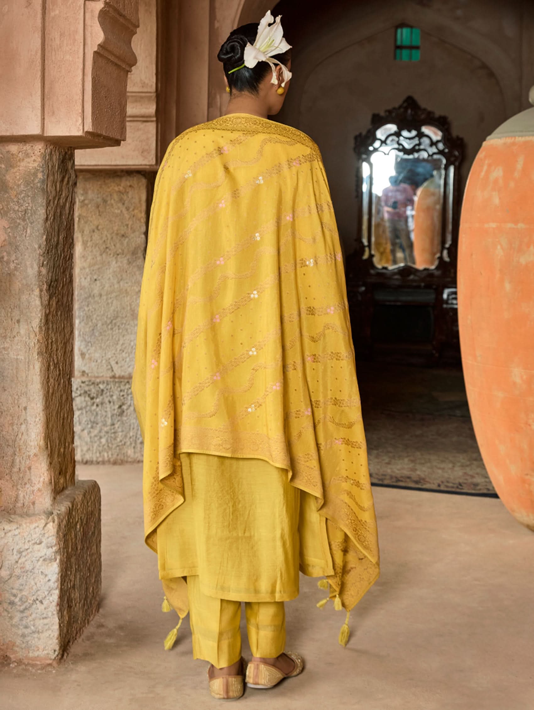Person wearing a yellow traditional outfit in an architectural setting.