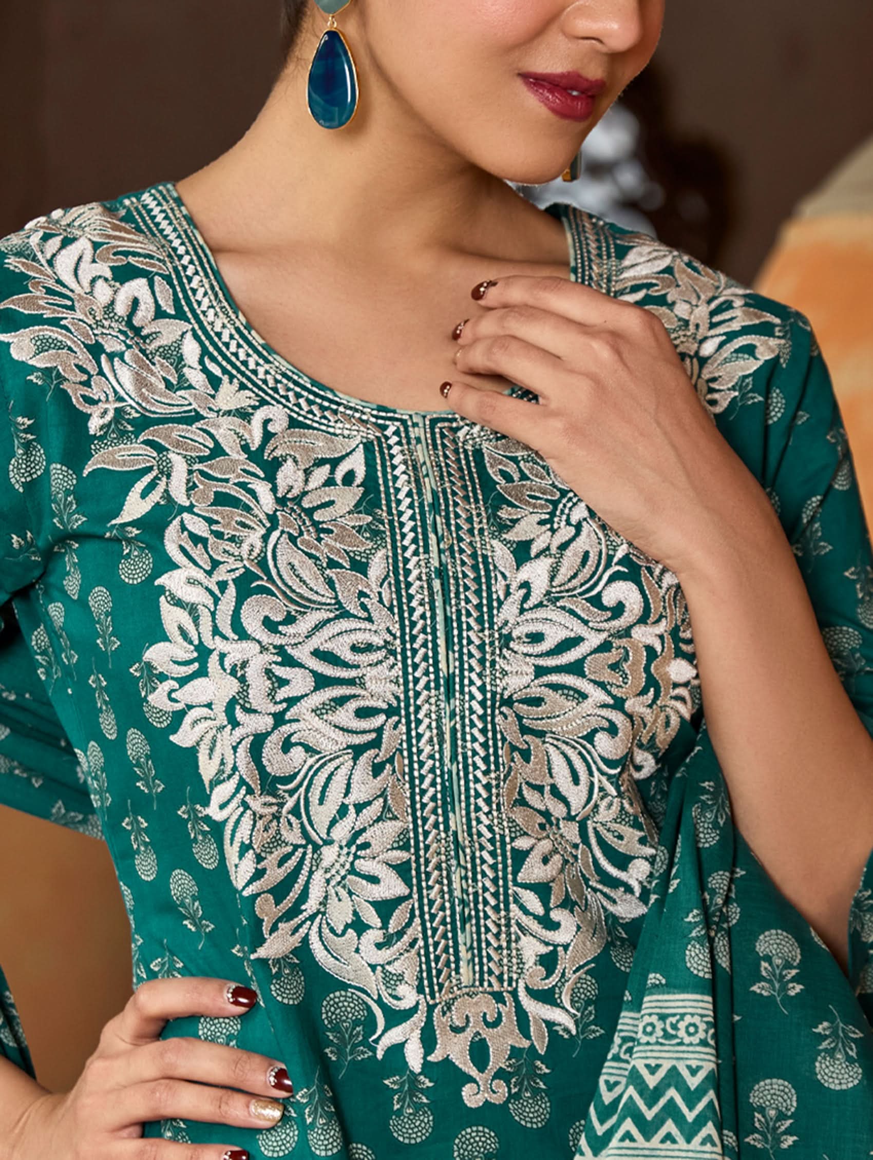 A woman wearing a green and white embroidered pure cotton suit set with three-quarter sleeves and side slits, including straight pants and a printed cotton dupatta.
