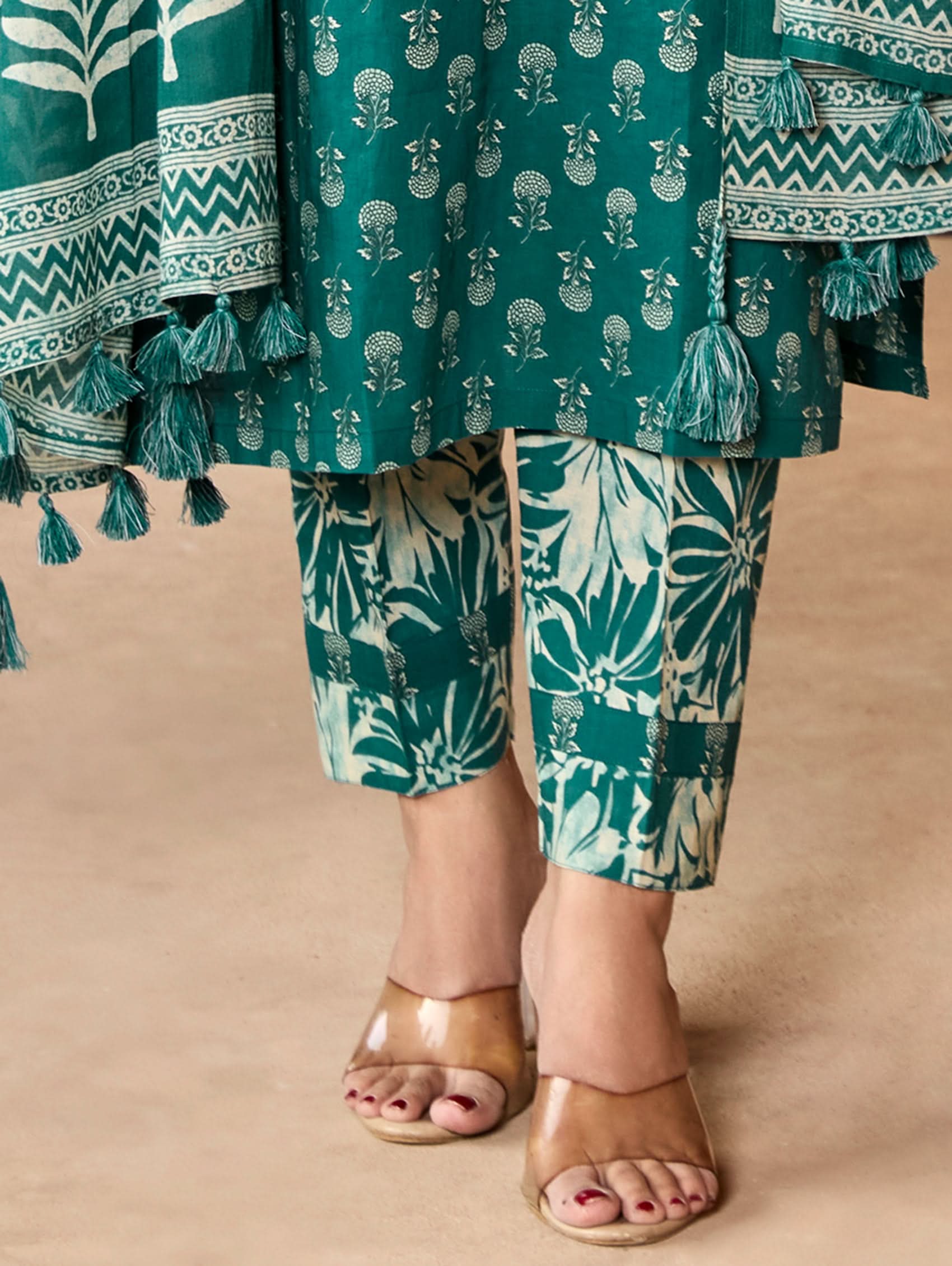 A woman wearing a green and white embroidered pure cotton suit set with three-quarter sleeves and side slits, including straight pants and a printed cotton dupatta.